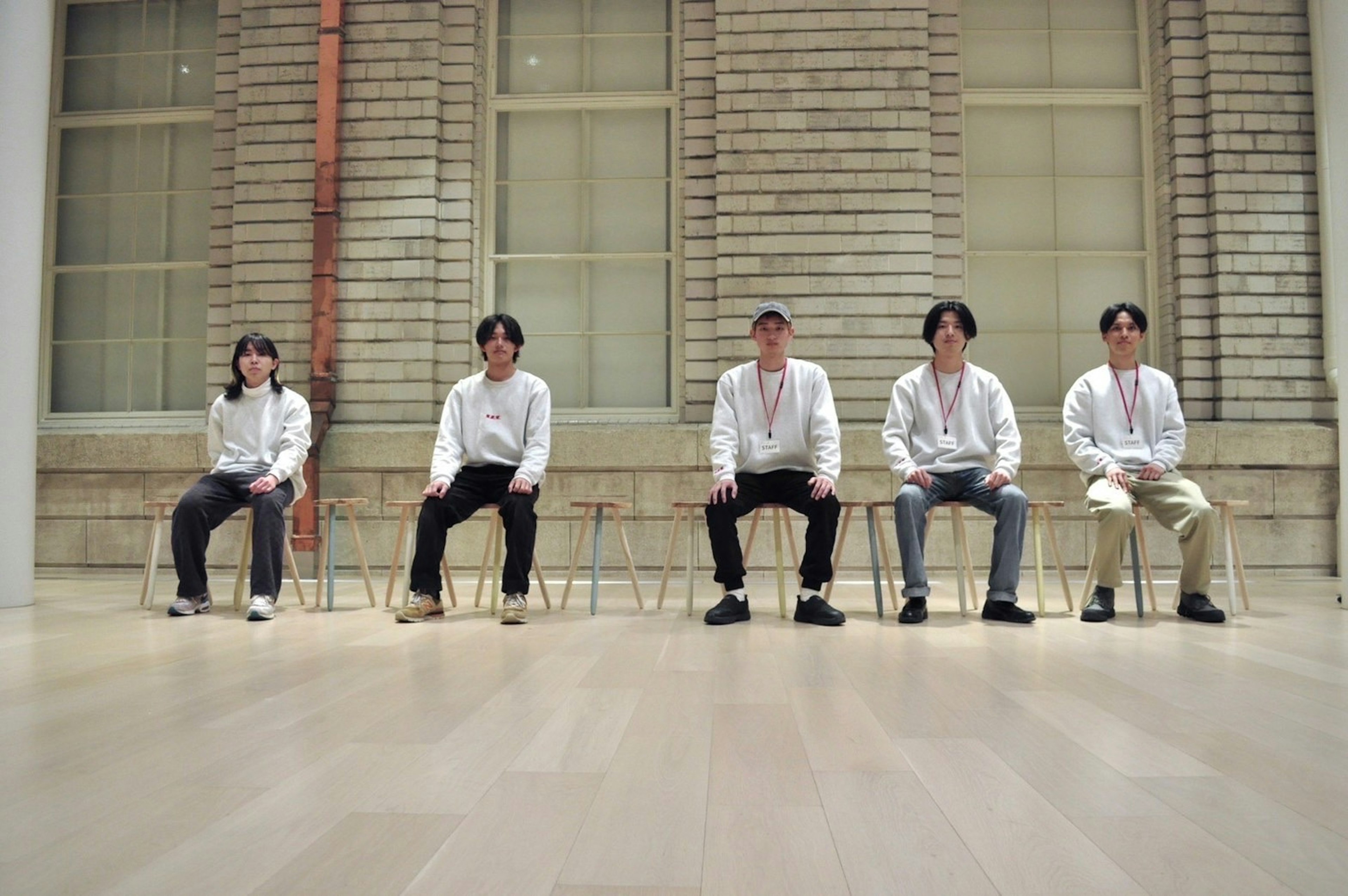 Five men in white shirts sitting in a simple indoor setting