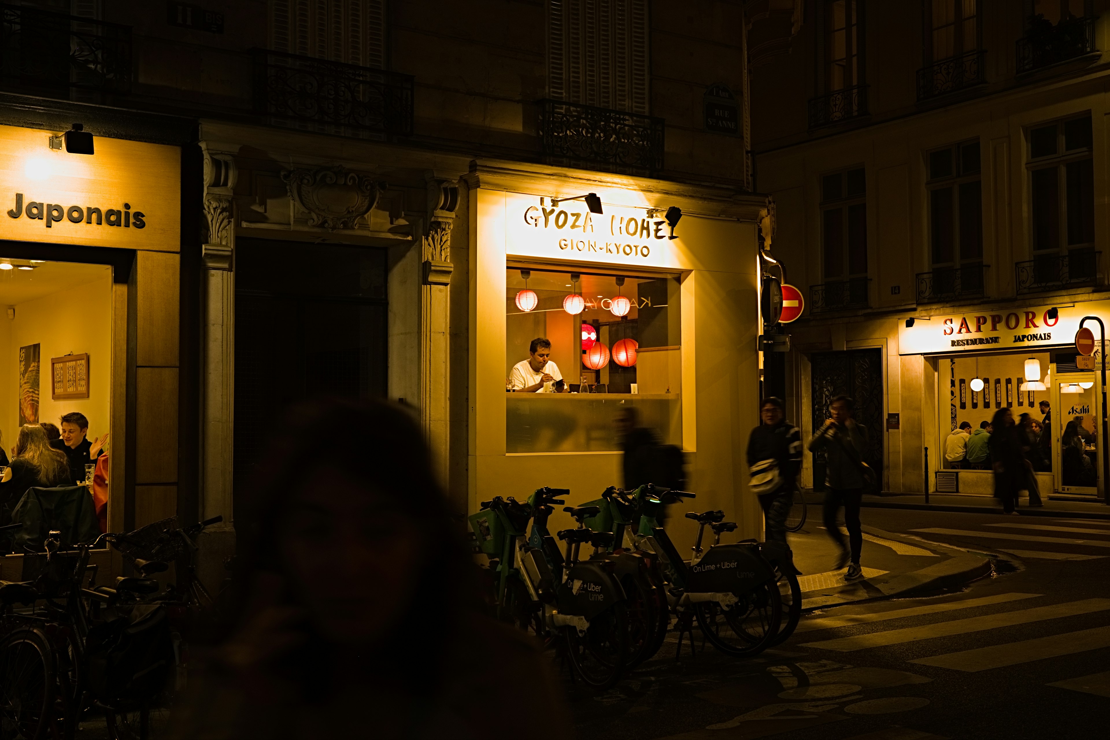 Extérieur d'un restaurant japonais dans une rue de Paris la nuit avec des lumières vives