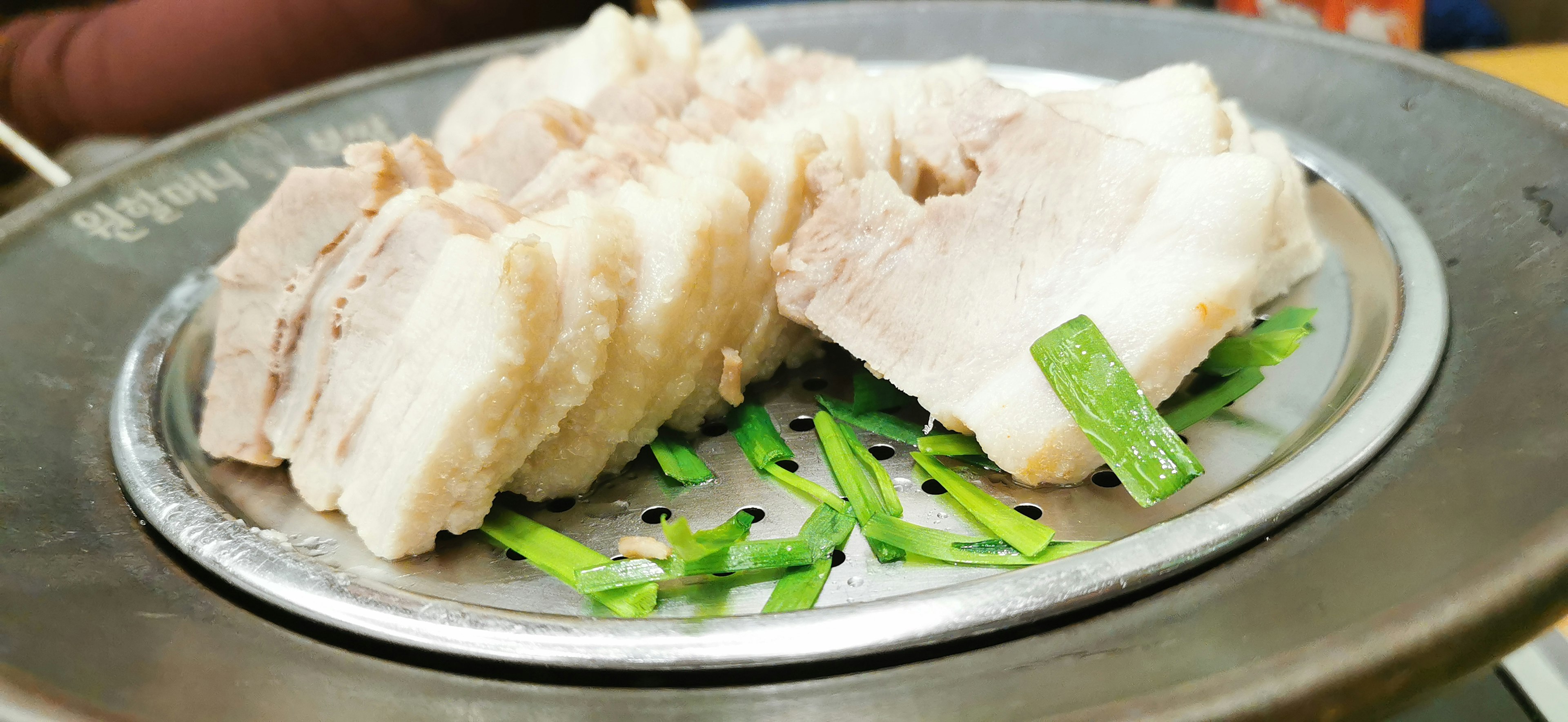 Sliced pork belly served with green onions on a plate