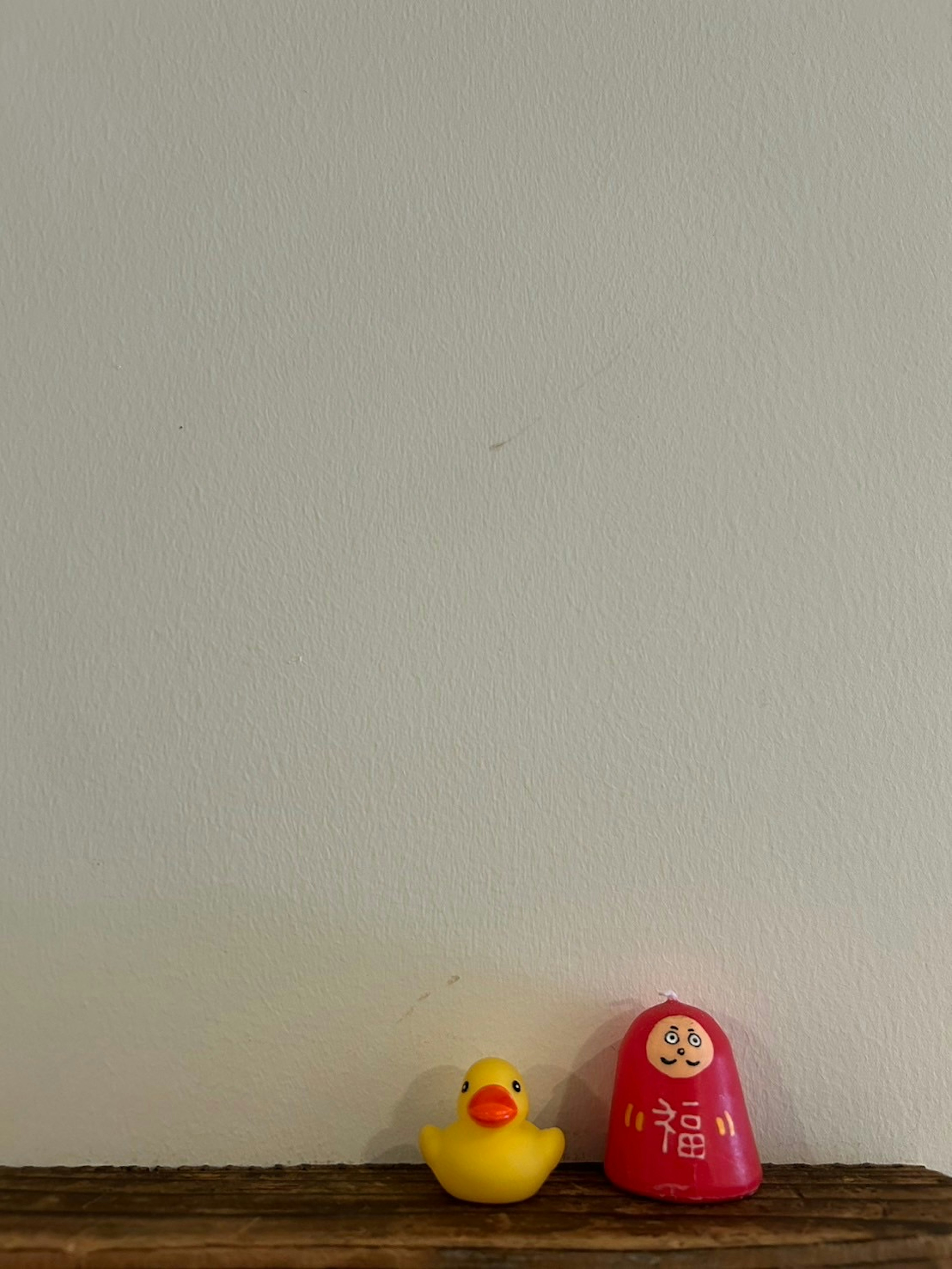 Un pato de goma amarillo y una campana roja sobre una mesa de madera