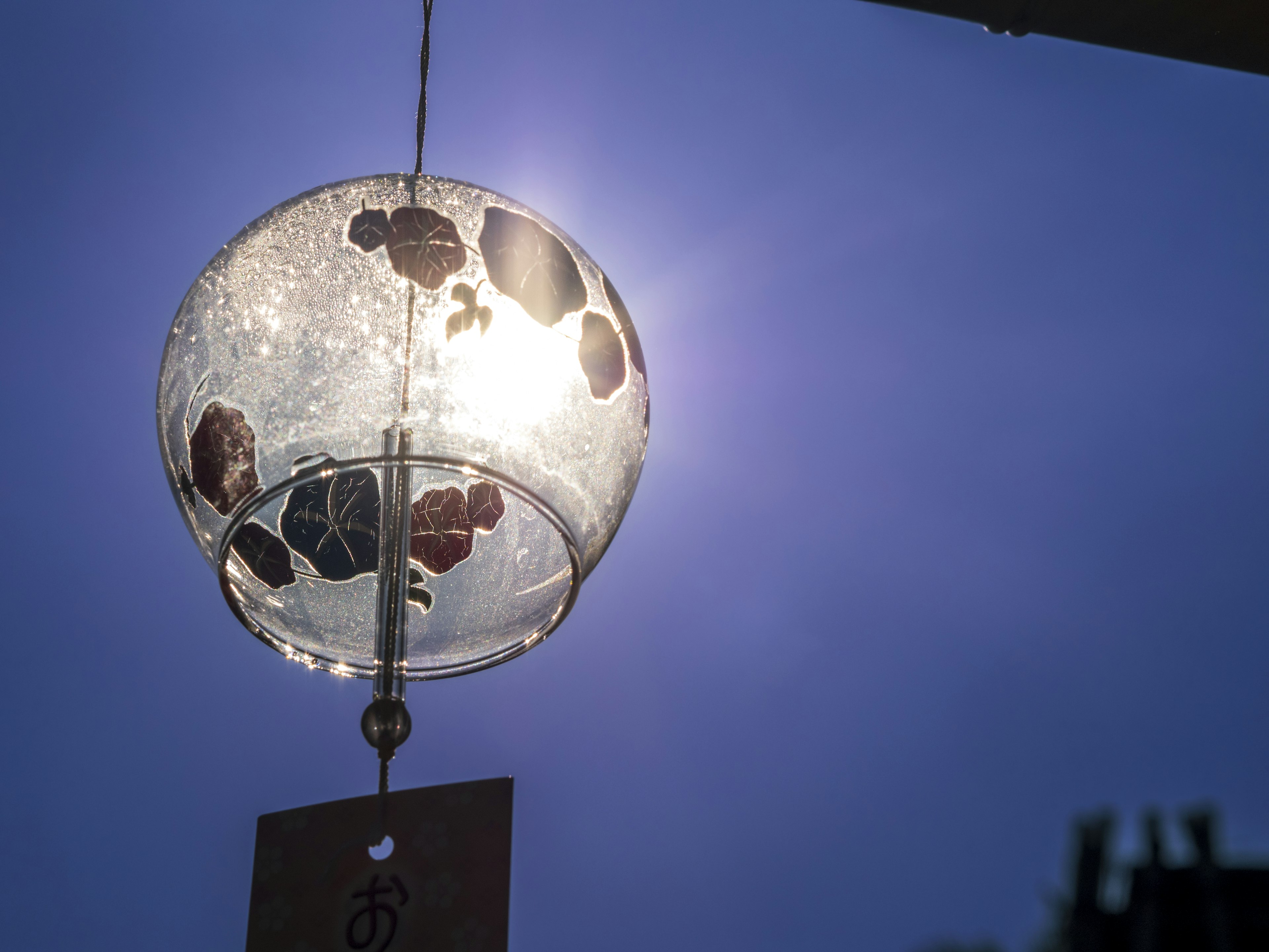 Beautiful glass lantern hanging under a blue sky Light shining through reflects colors