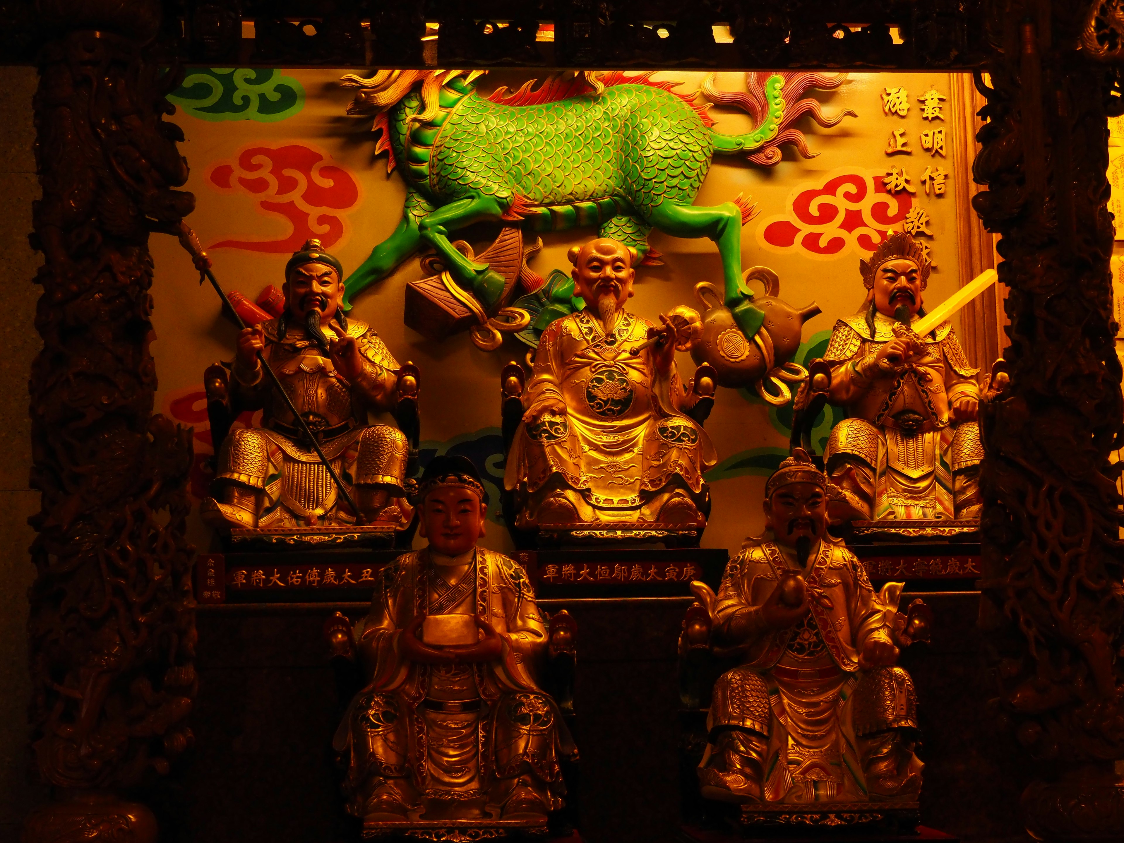 Golden statues of deities arranged with a green horse figure in the background