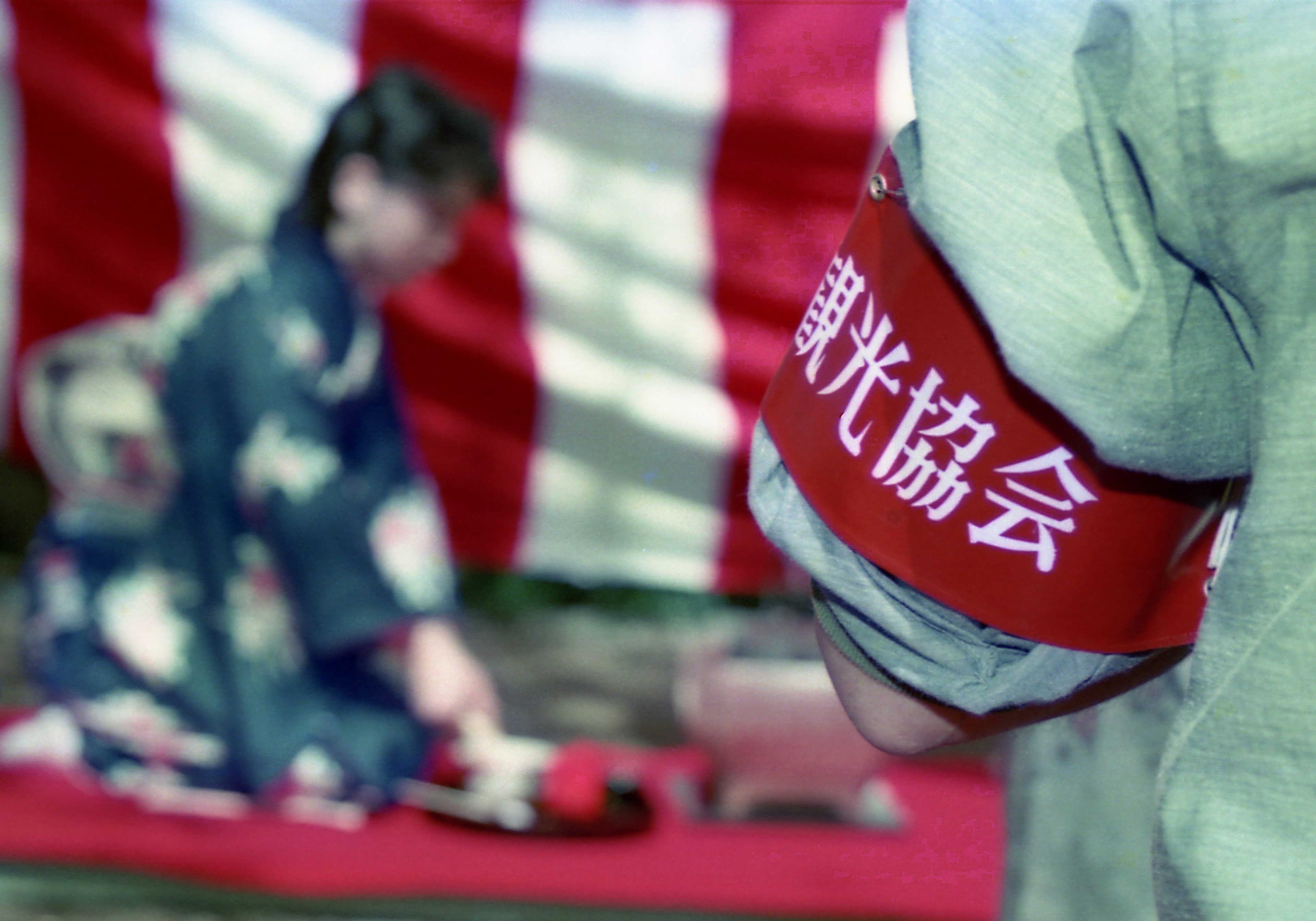 Person in kimono with red band showing text and striped backdrop