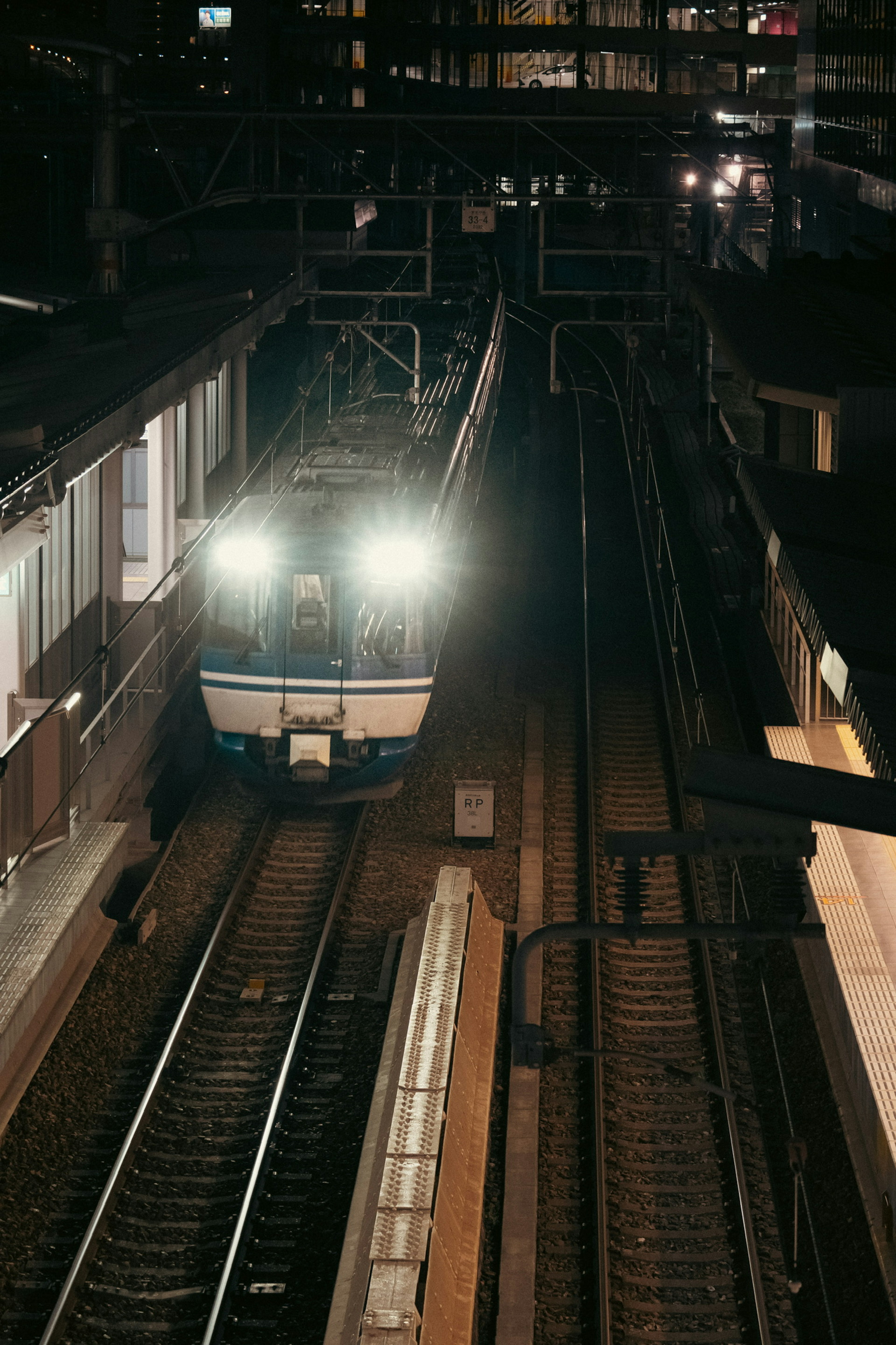 Train arriving at night station with bright headlights