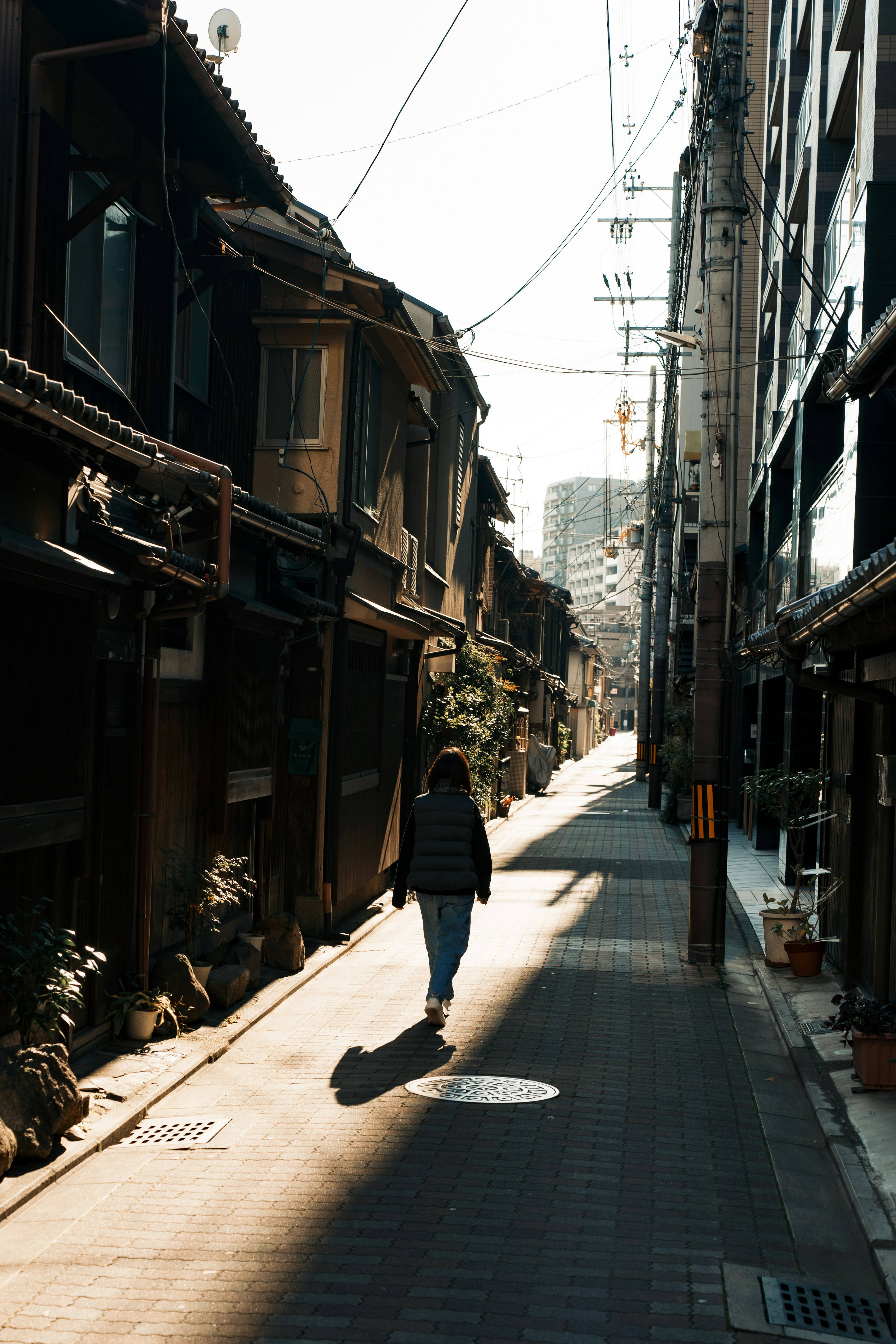 A person walking in a quiet alley with old buildings and shadows