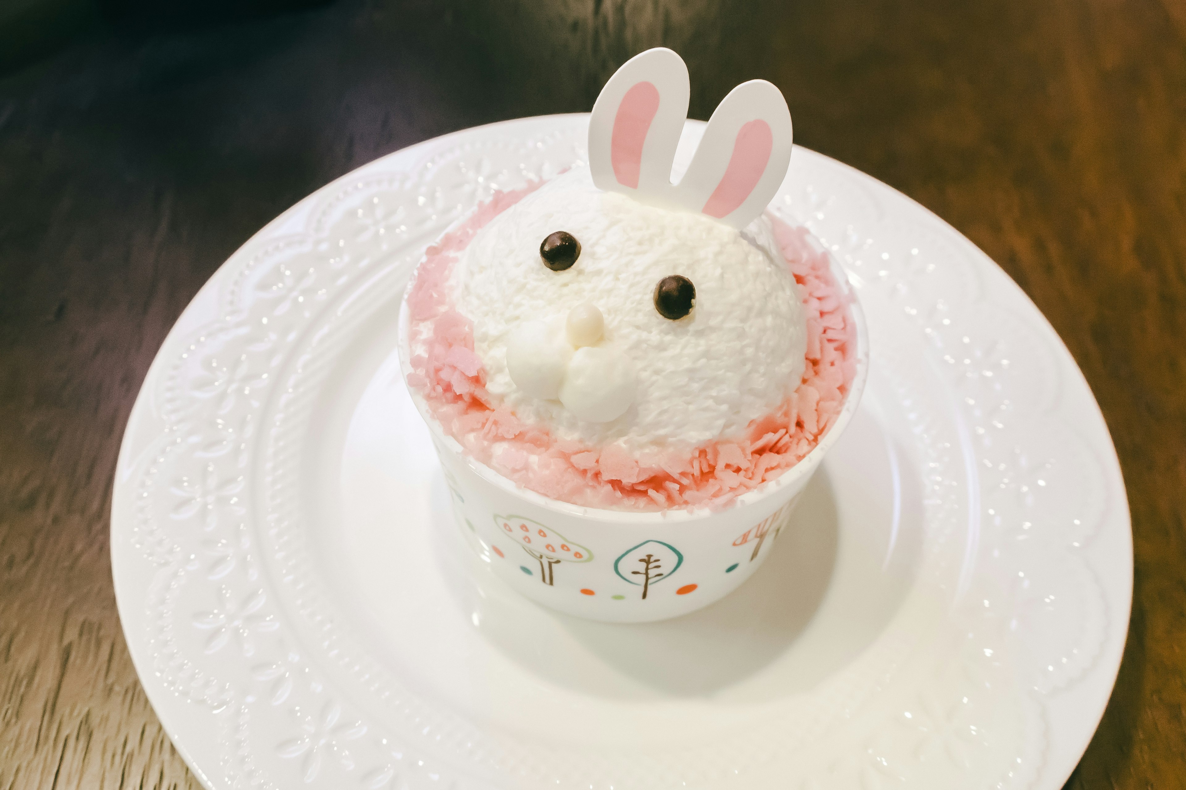 Dessert en forme de lapin décoré de crème rose sur une assiette blanche