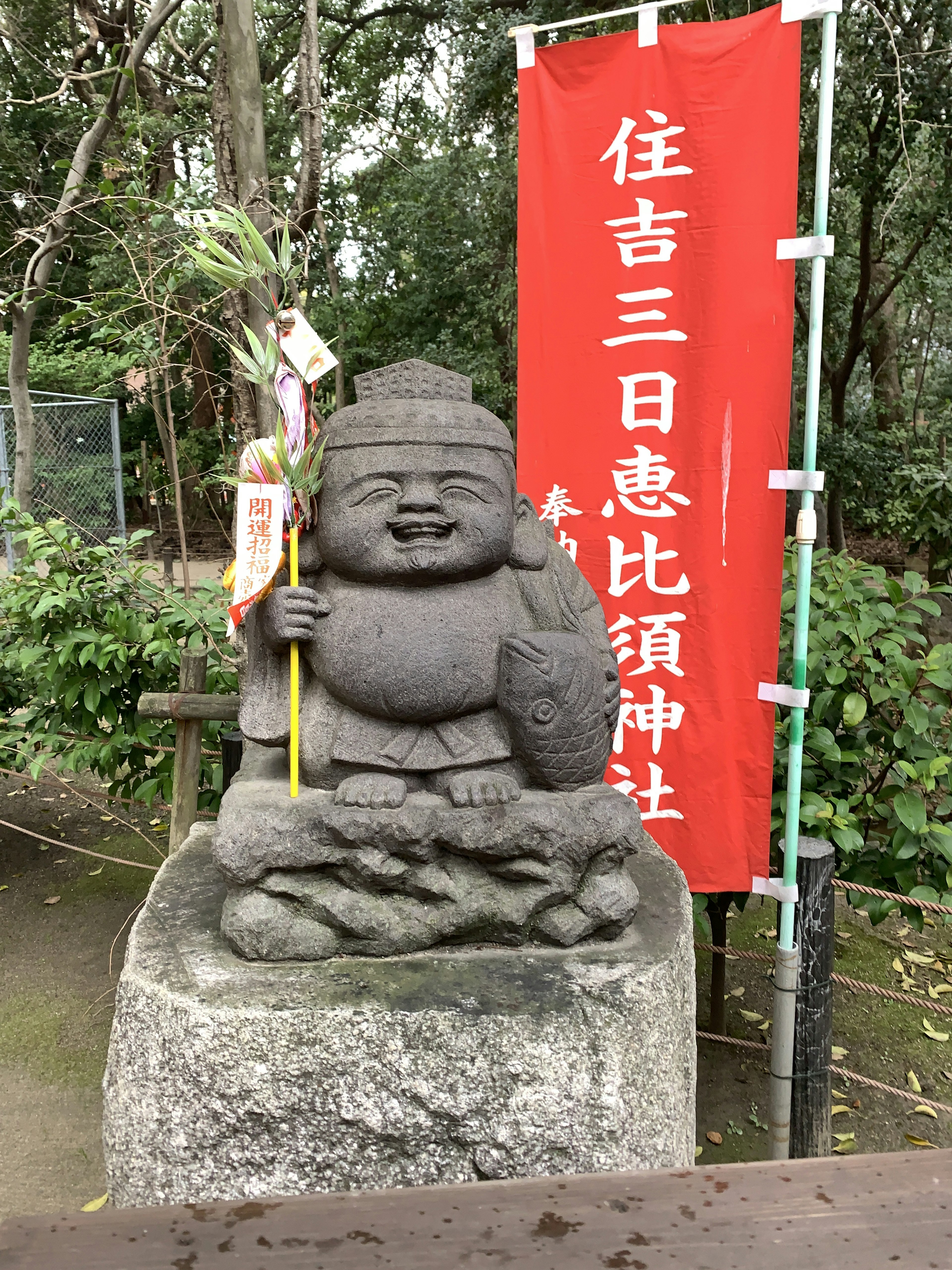 Stone statue of a deity standing in front of a red banner smiling