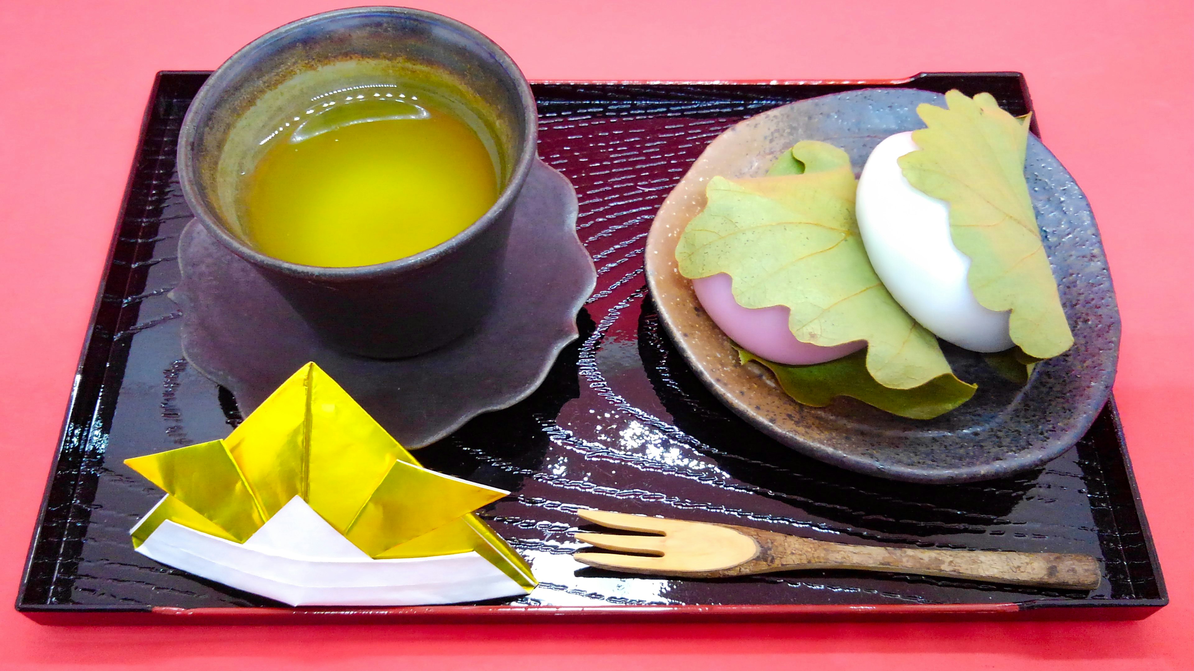 緑茶と和菓子のプレートに折り紙の船が添えられた風景