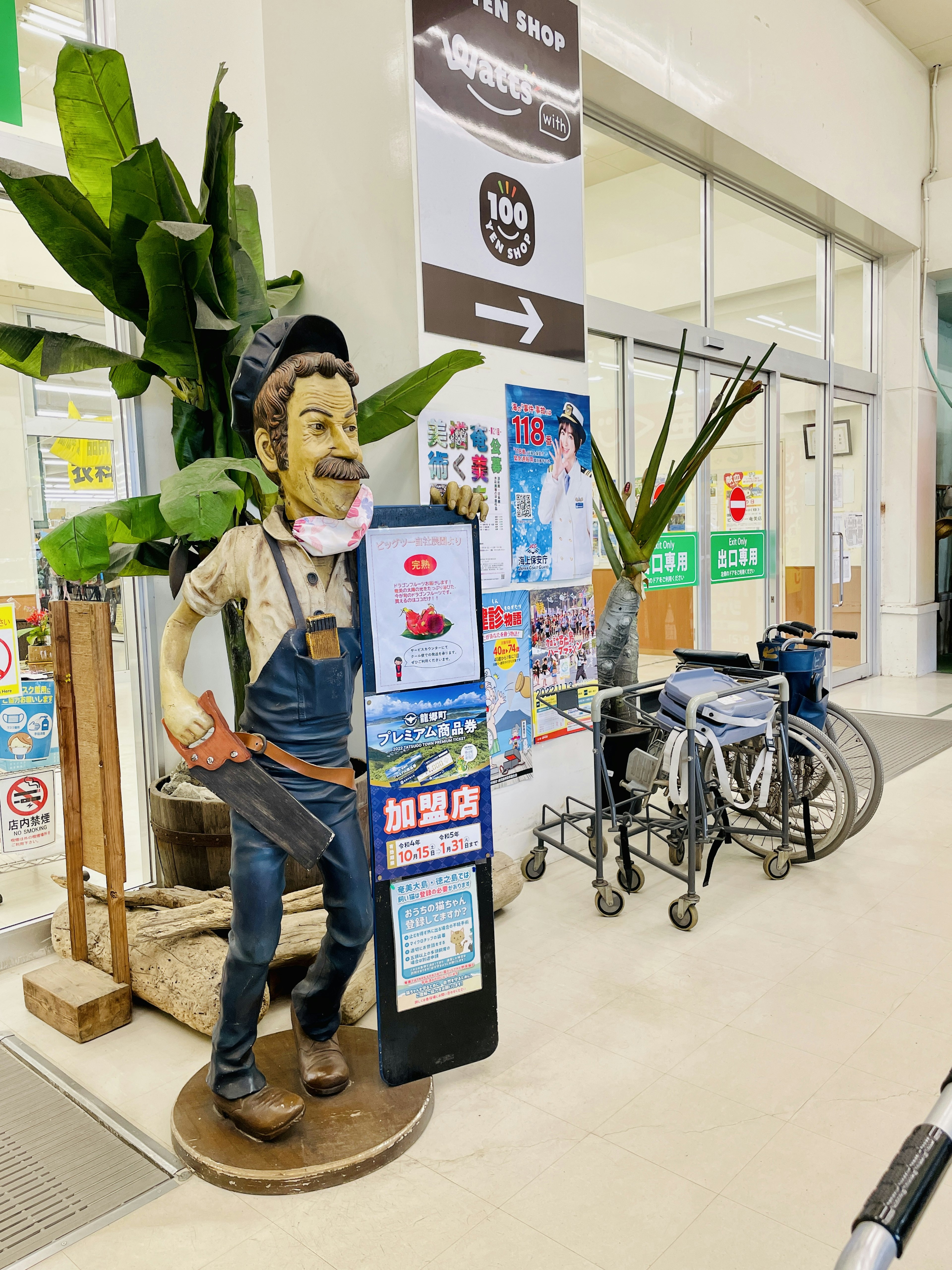 Un maniquí de un hombre con overoles azules de pie en la entrada de la tienda