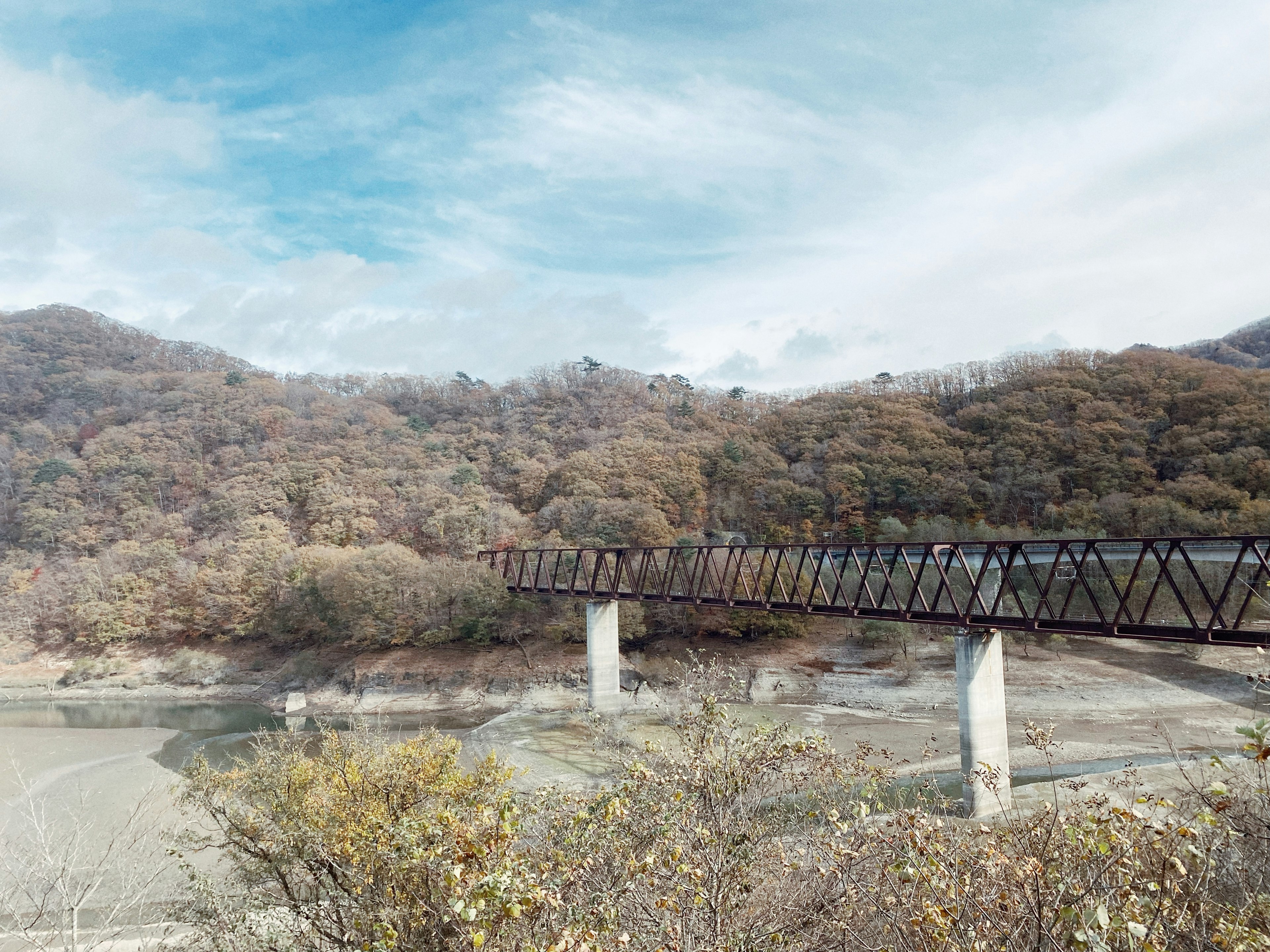 山々に囲まれた古い鉄橋と穏やかな川の風景