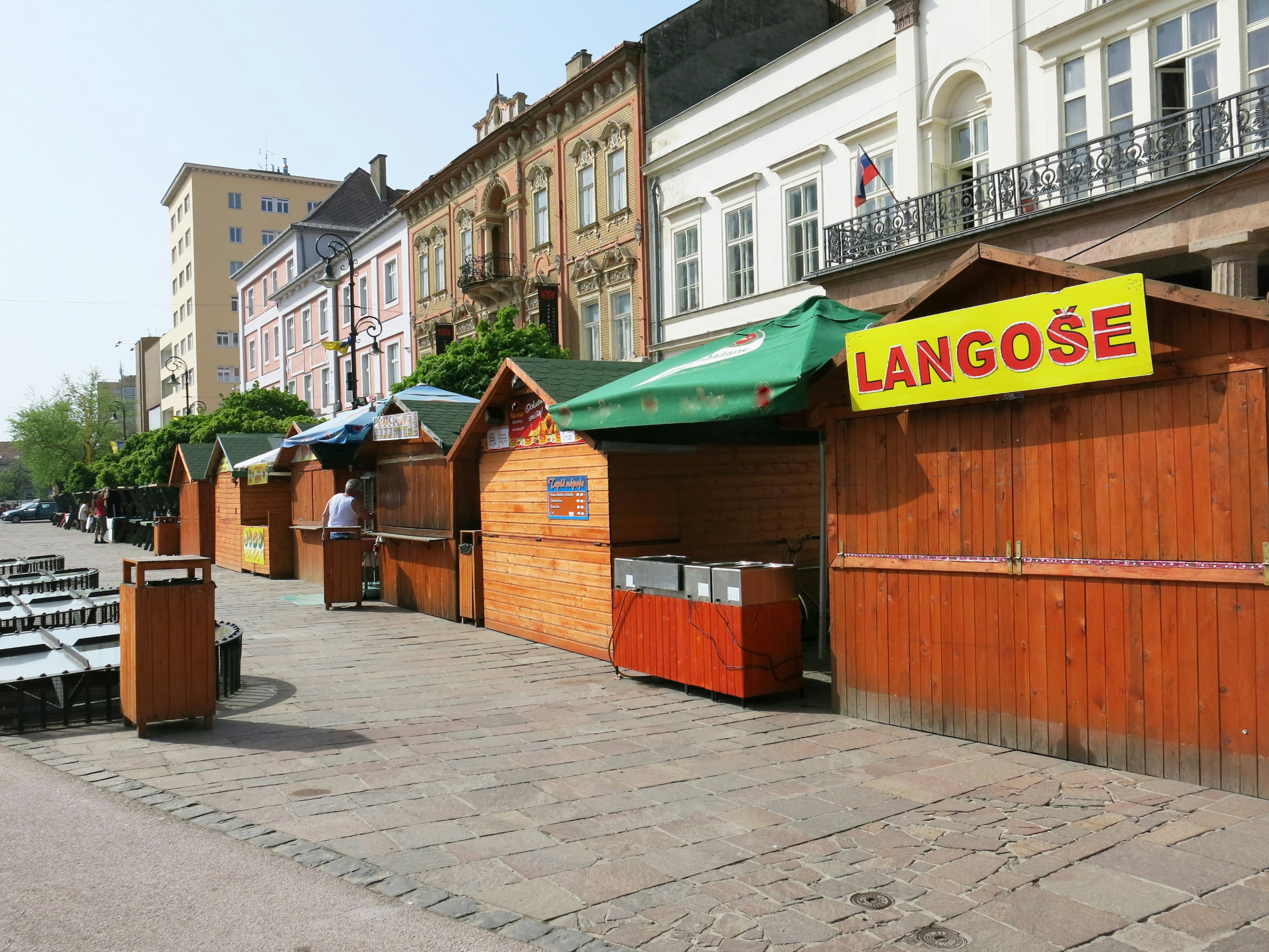 Street scene featuring wooden stalls with a yellow sign reading LANGÖSE