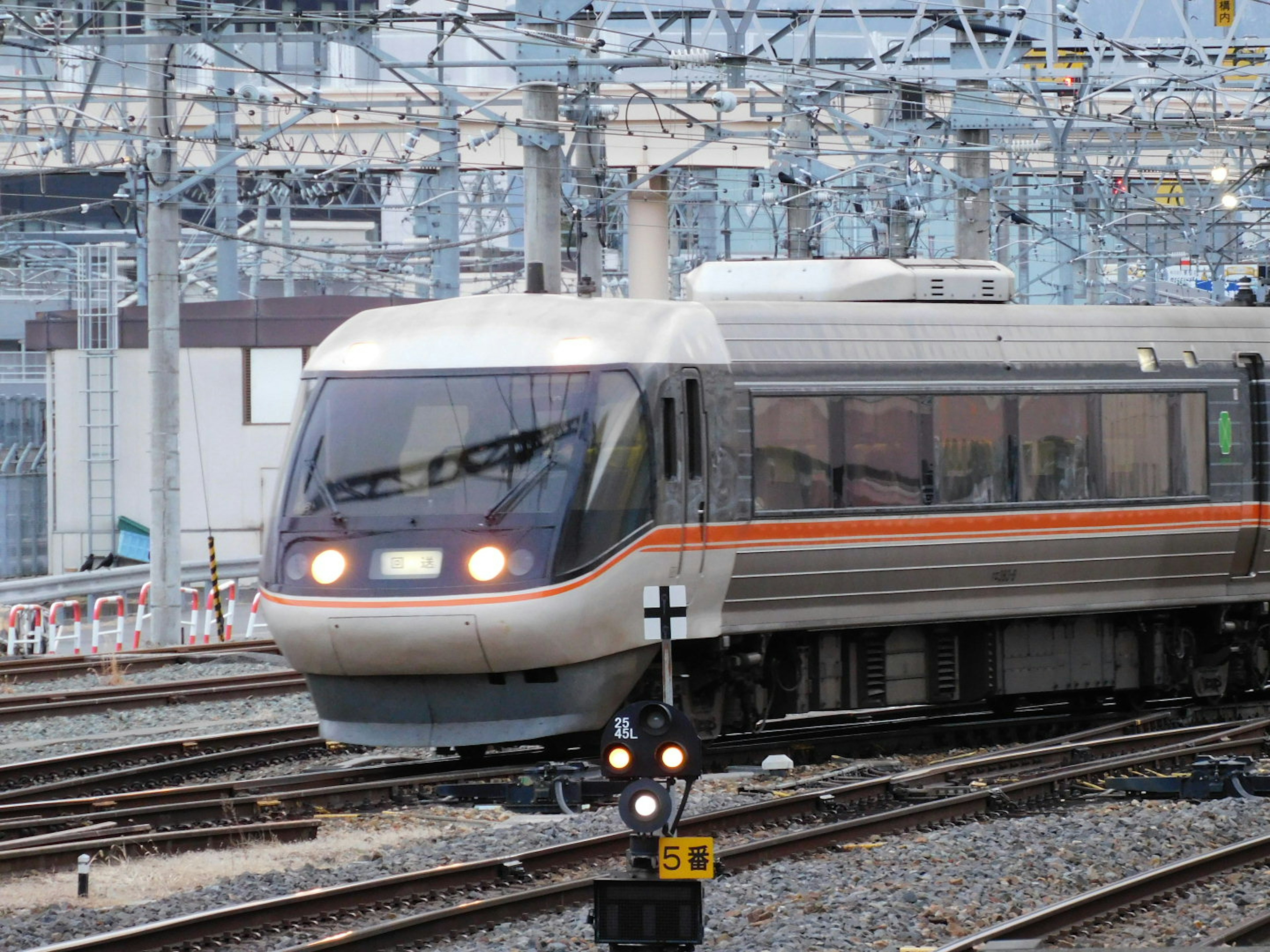 A Shinkansen train approaching a signal in a railway yard