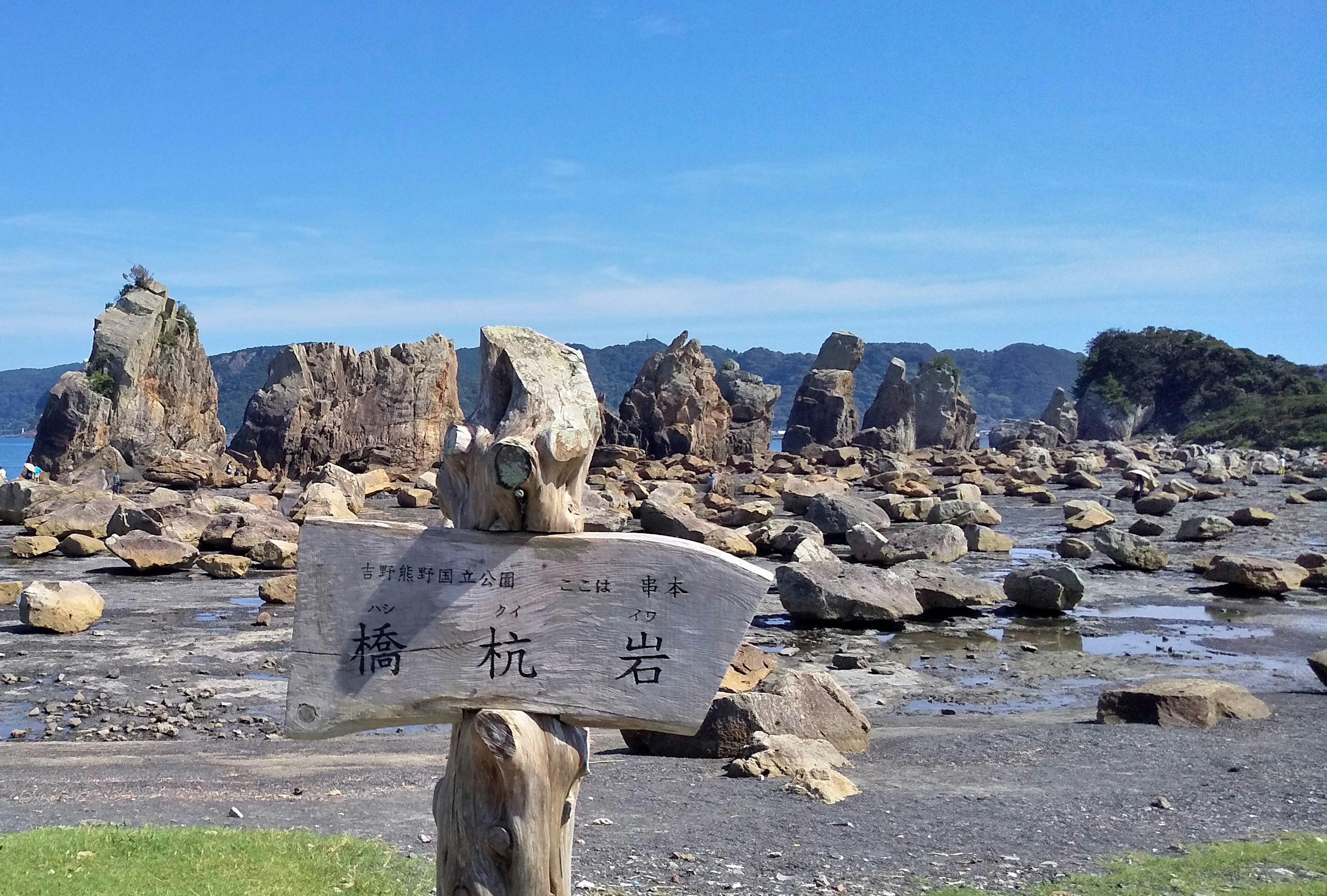 Coastal landscape with scattered rocks and a wooden sign