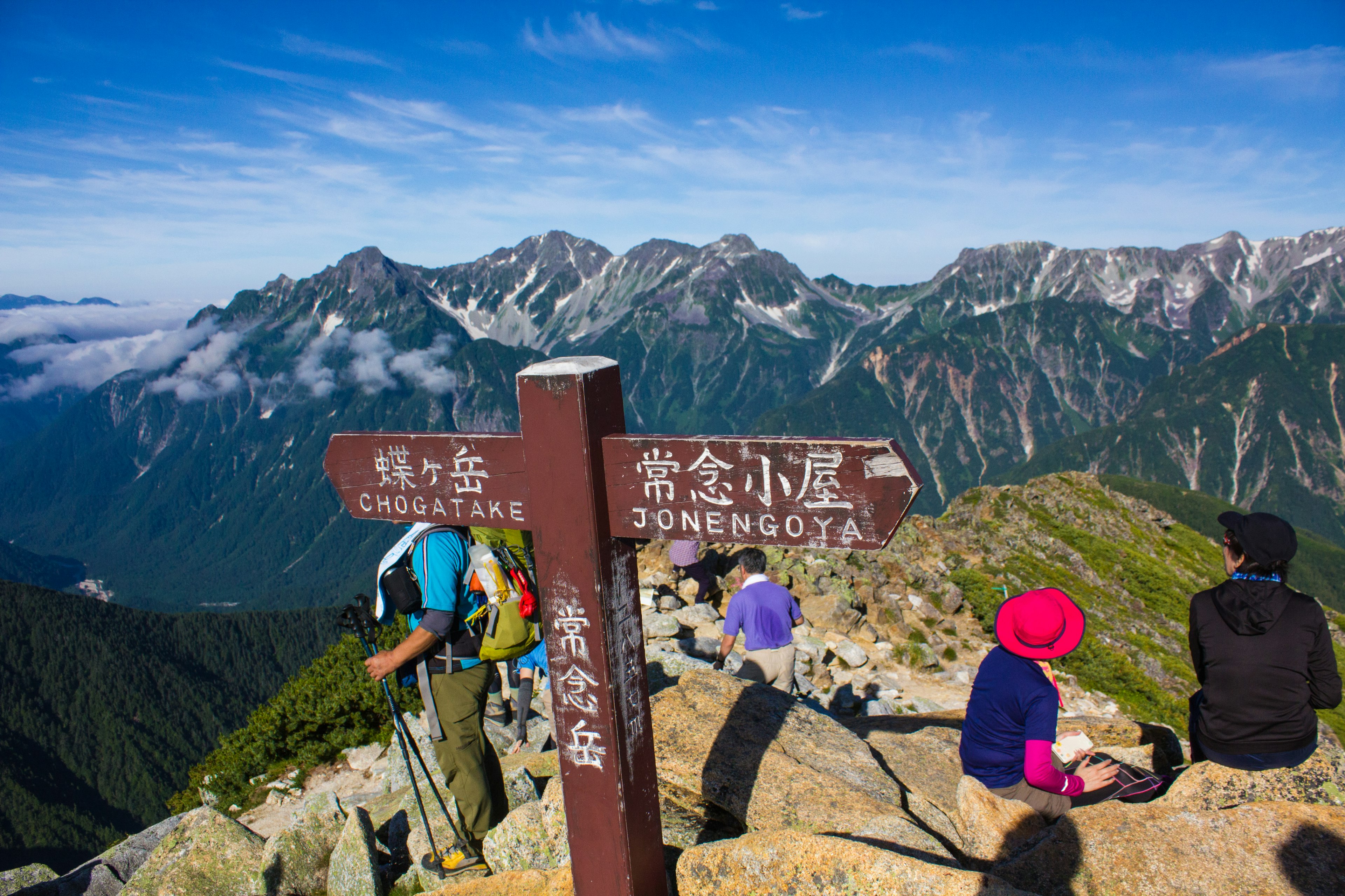 山の頂上に立つ登山者たちと道標の風景