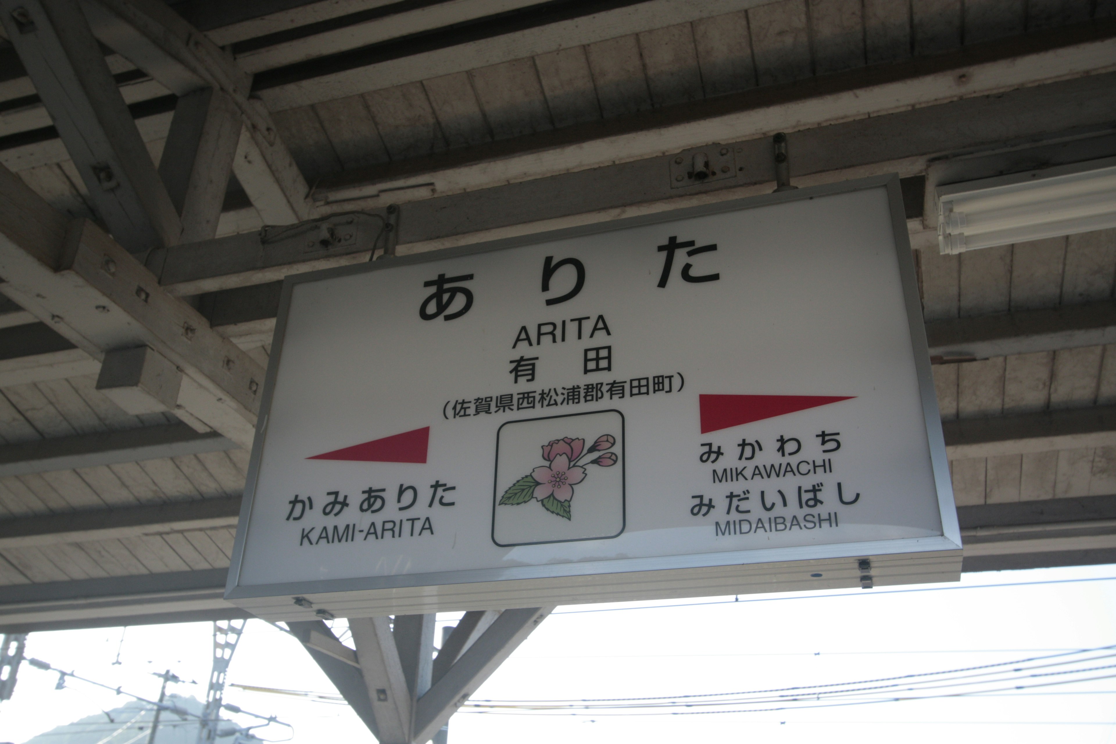 Station sign for Arita with directional arrows and Japanese characters