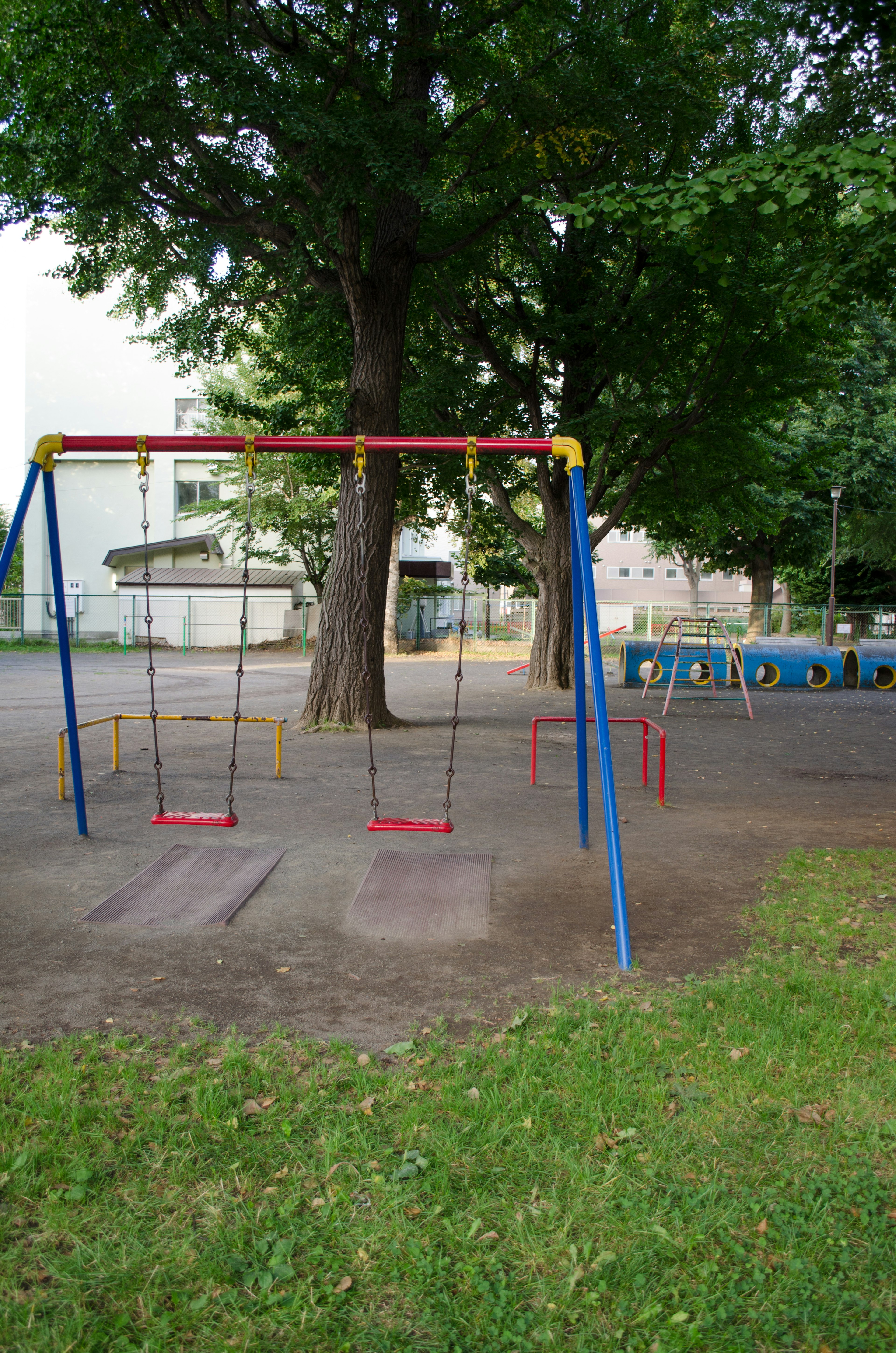 Playground swings with green trees in the background