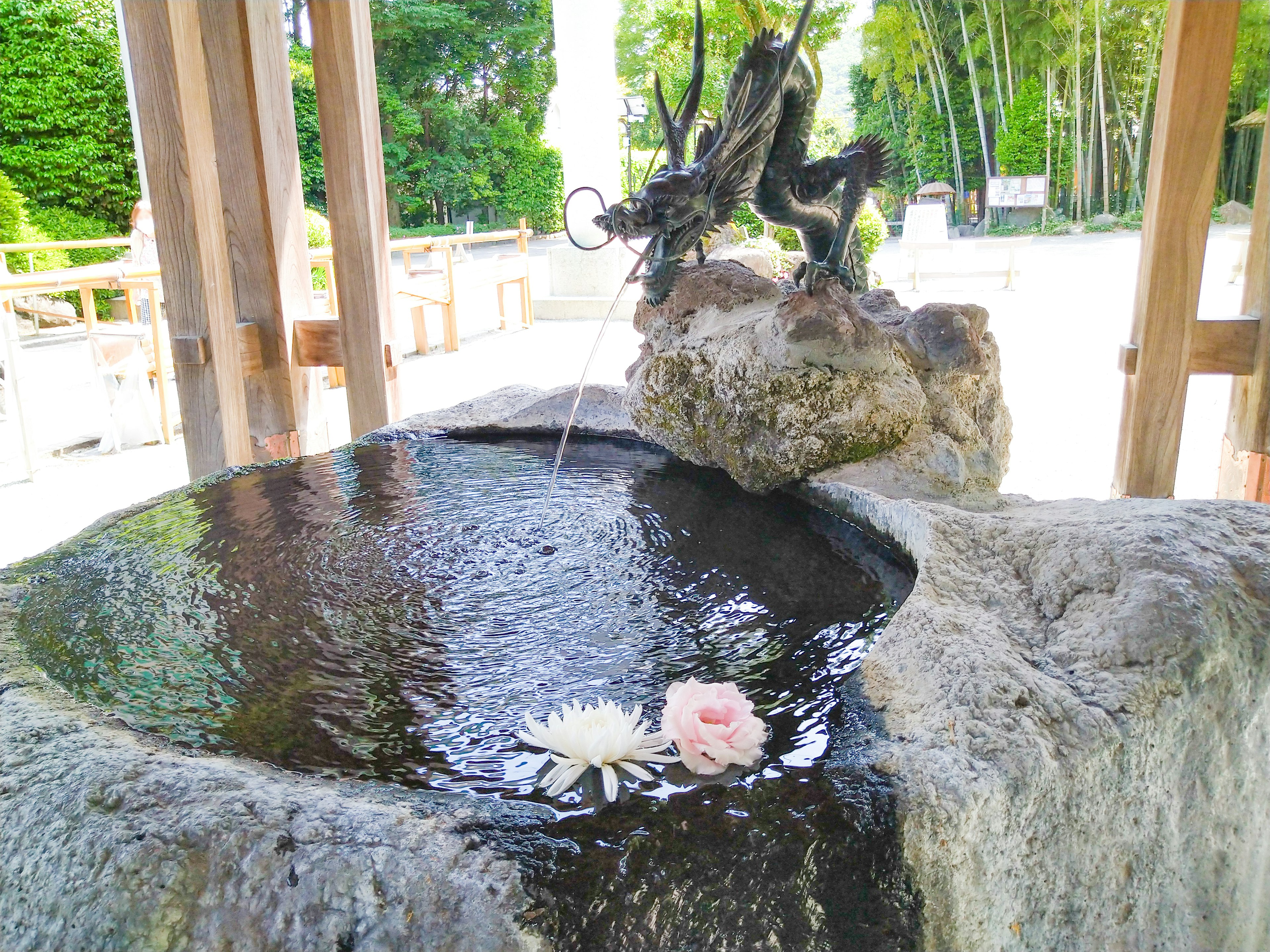 Bassin en pierre avec des fleurs flottantes et sculpture de dragon