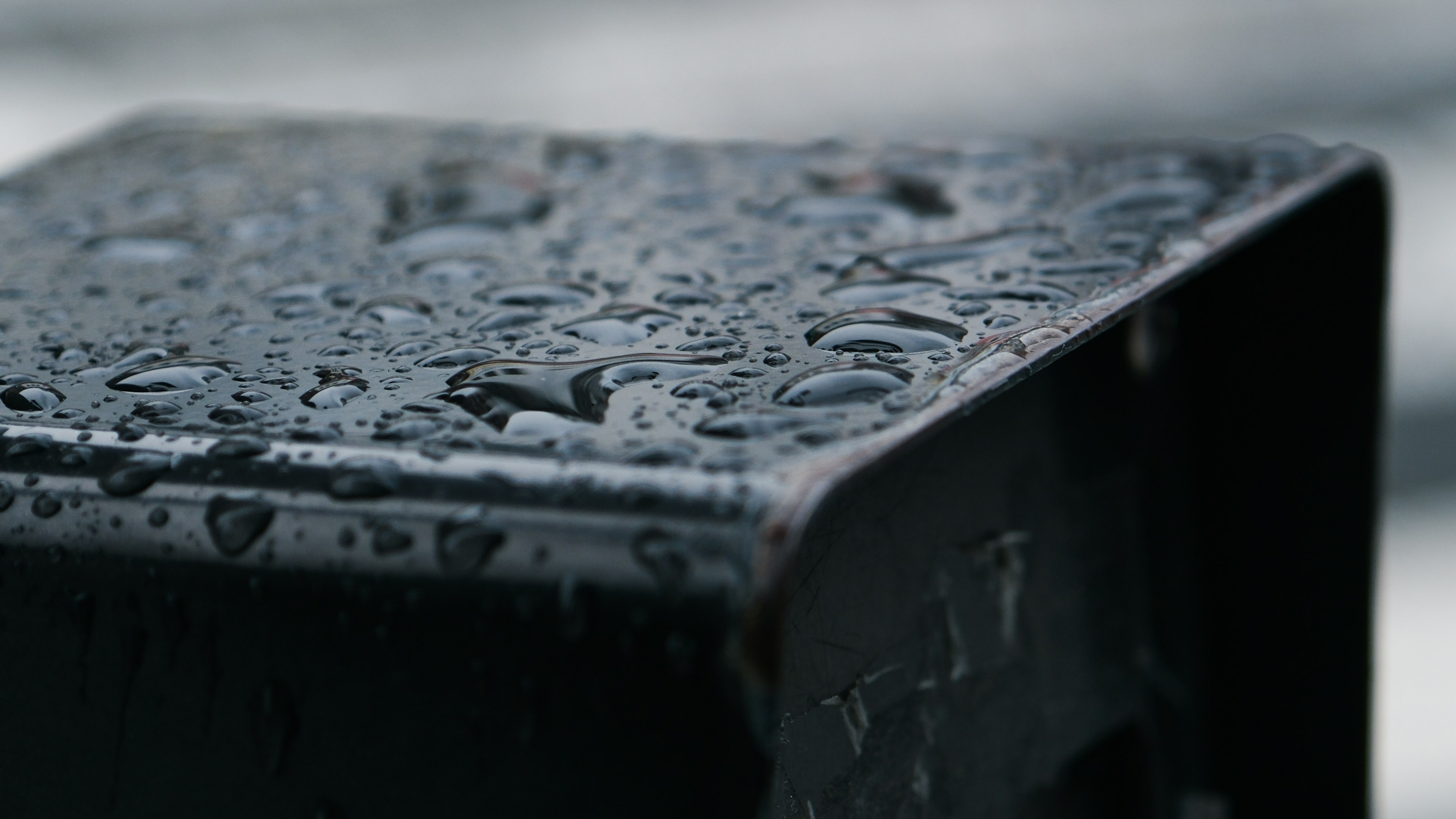 Primer plano de una esquina de metal negro con gotas de agua en la superficie