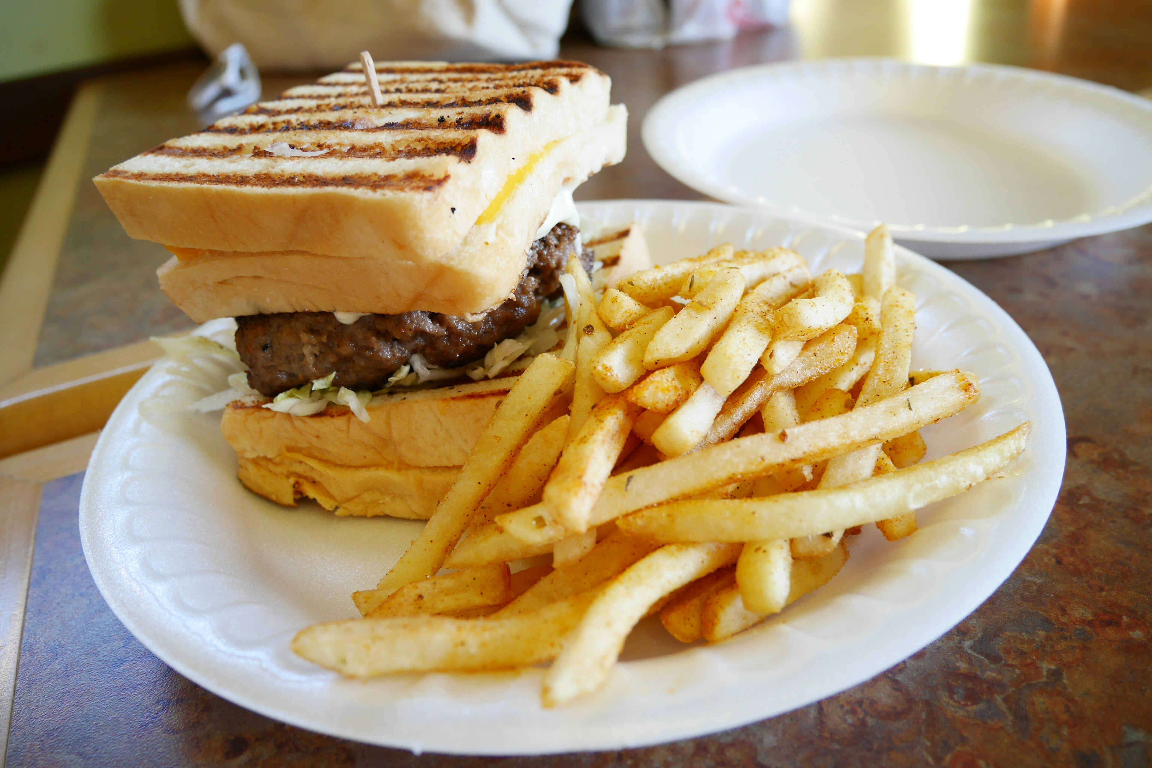 Sandwich panggang dengan kentang goreng di piring putih