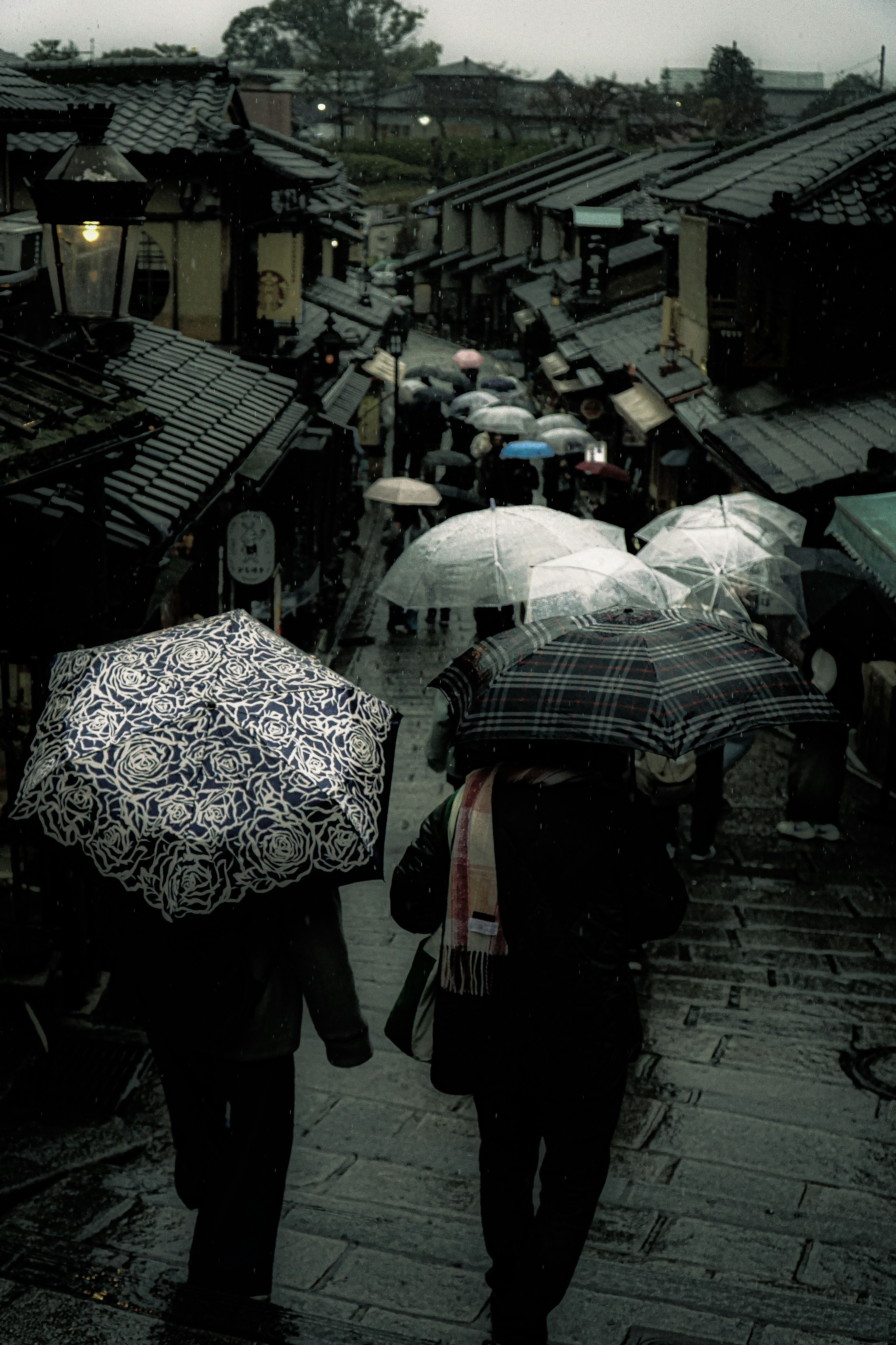 Rue de Kyoto par un jour de pluie avec des gens tenant des parapluies bâtiments traditionnels le long du chemin