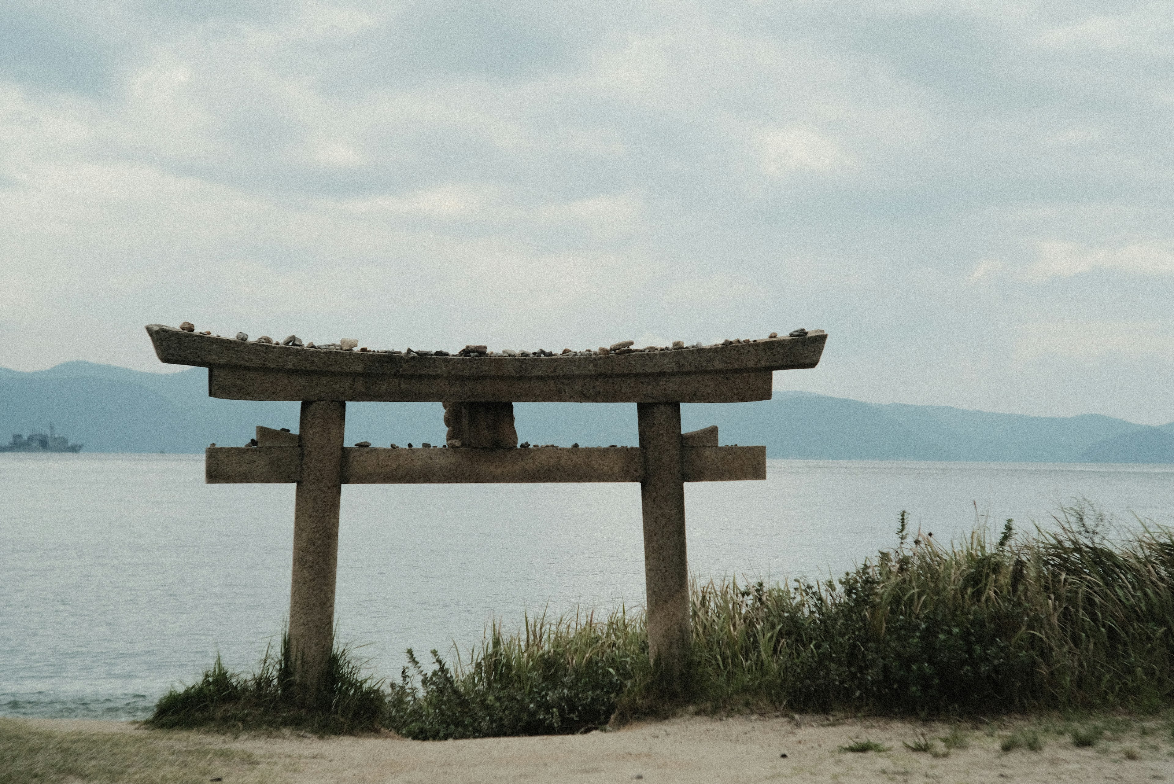 海に面した古い鳥居と草原の風景