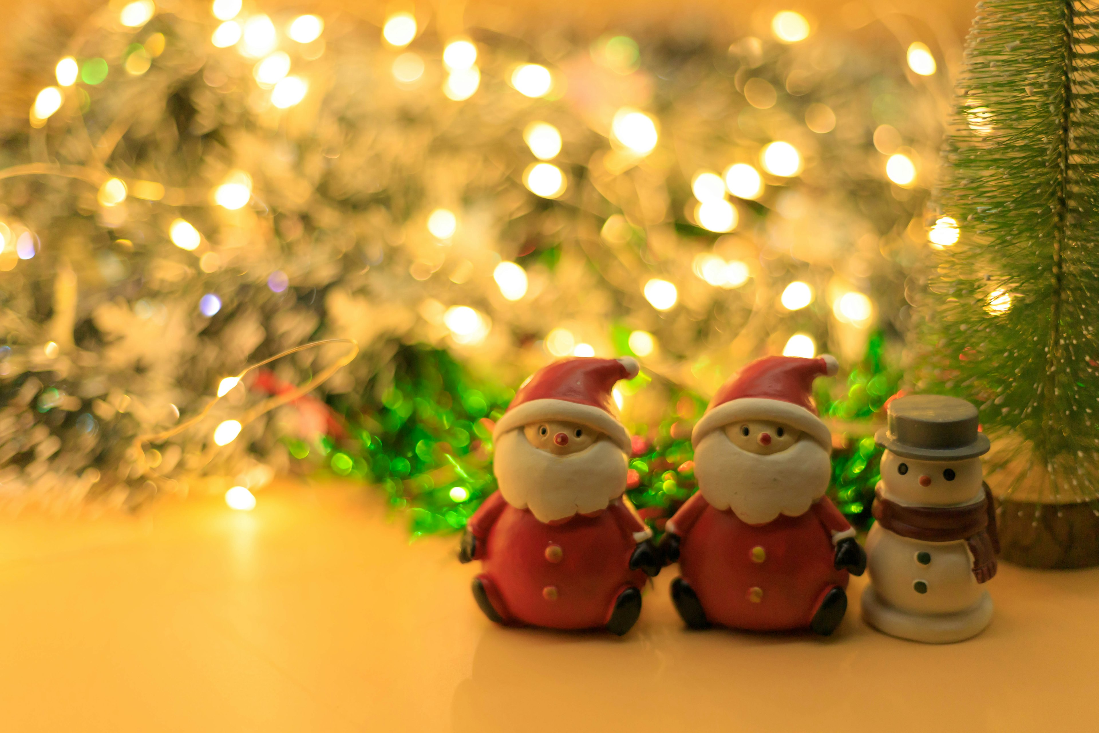 Christmas figurines of Santa Claus and a snowman with twinkling lights in the background