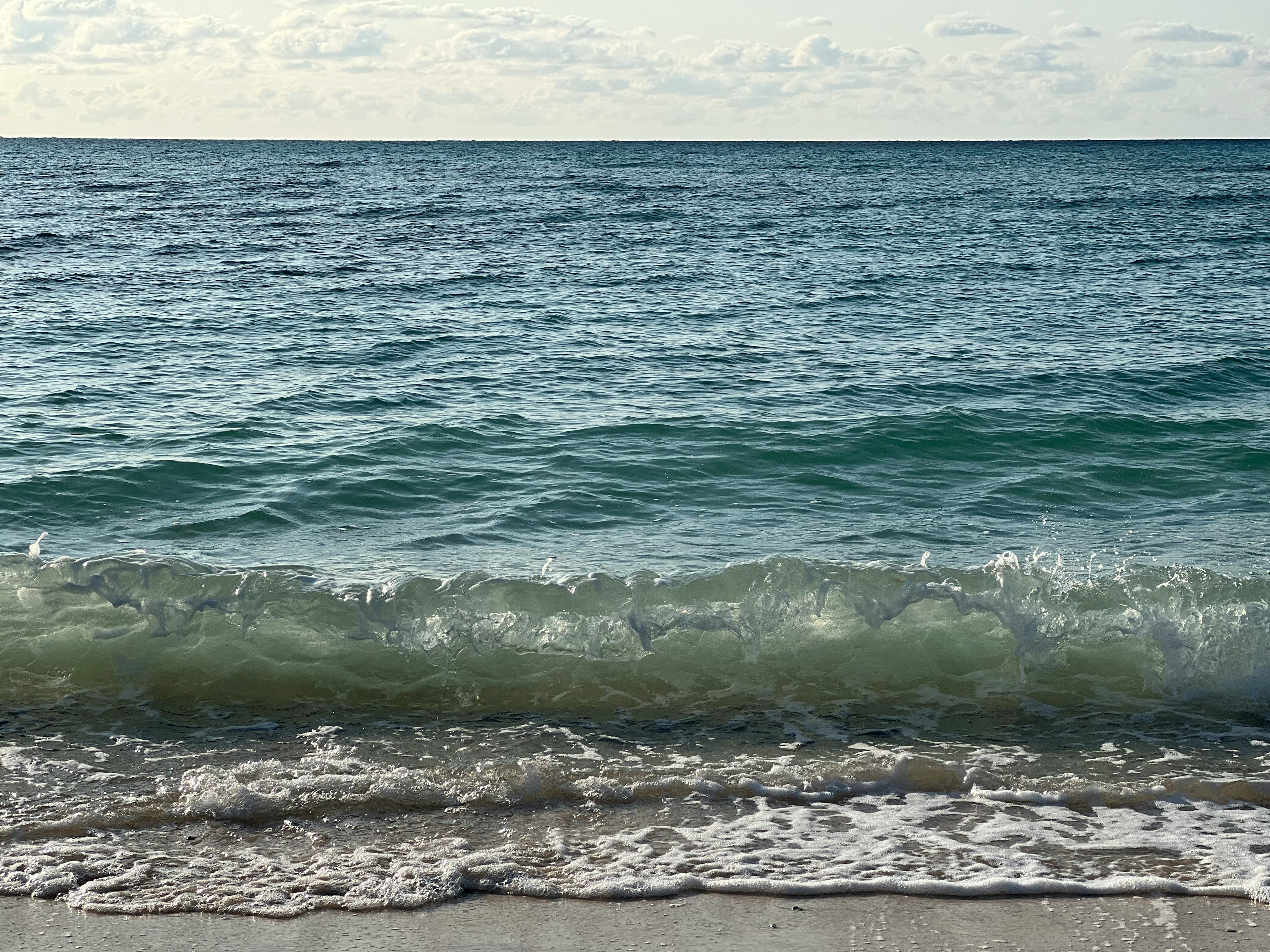 Beruhigte Ozeanwellen, die sanft auf den Sandstrand rollen