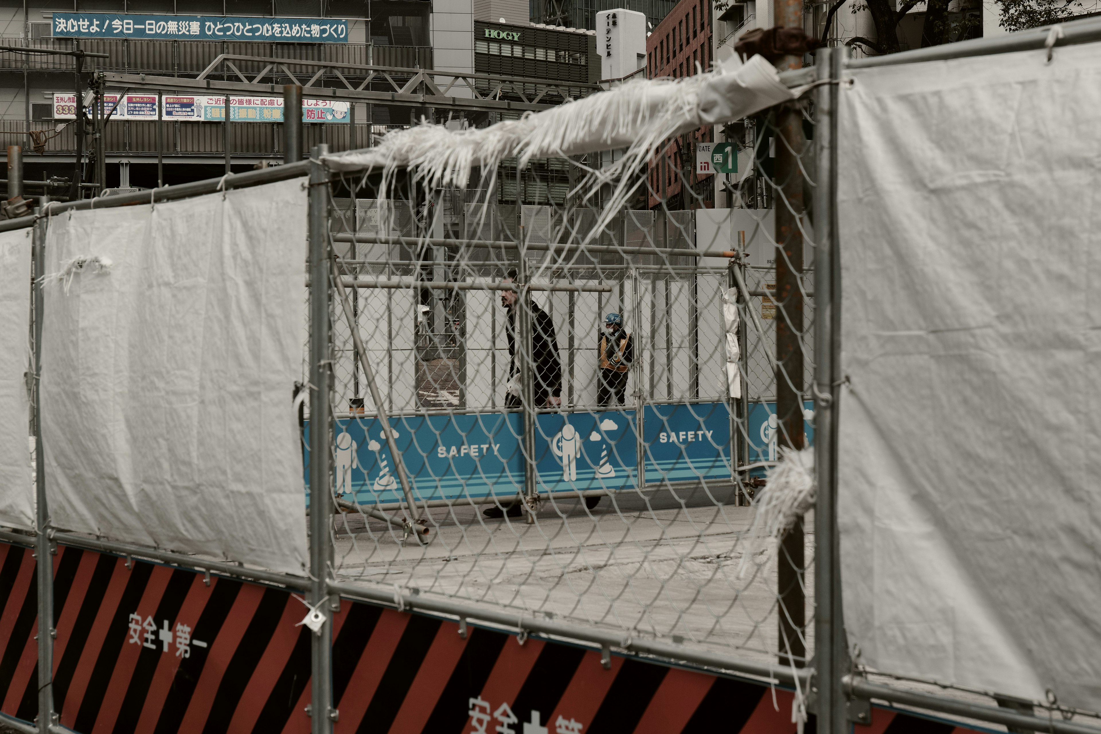 Zone de construction entourée d'une clôture avec des couvertures blanches et des publicités bleues