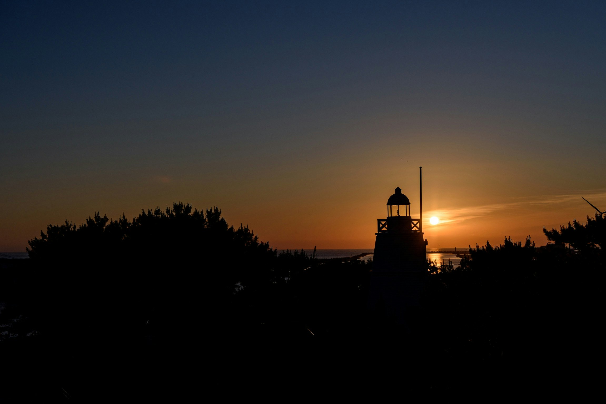 Silhouette of a lighthouse against a sunset