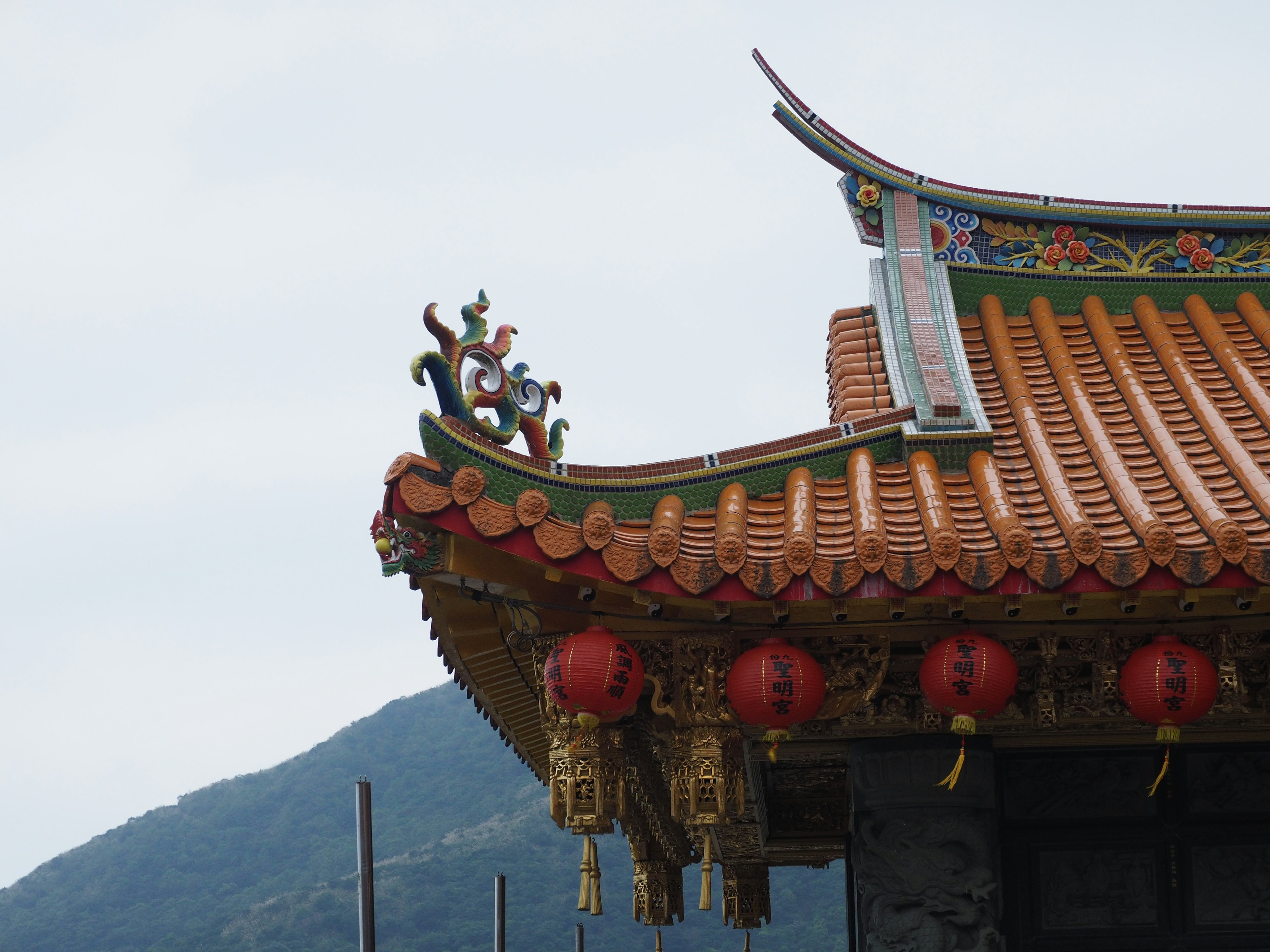 Détail du toit d'un bâtiment traditionnel chinois avec des éléments décoratifs et des lanternes rouges