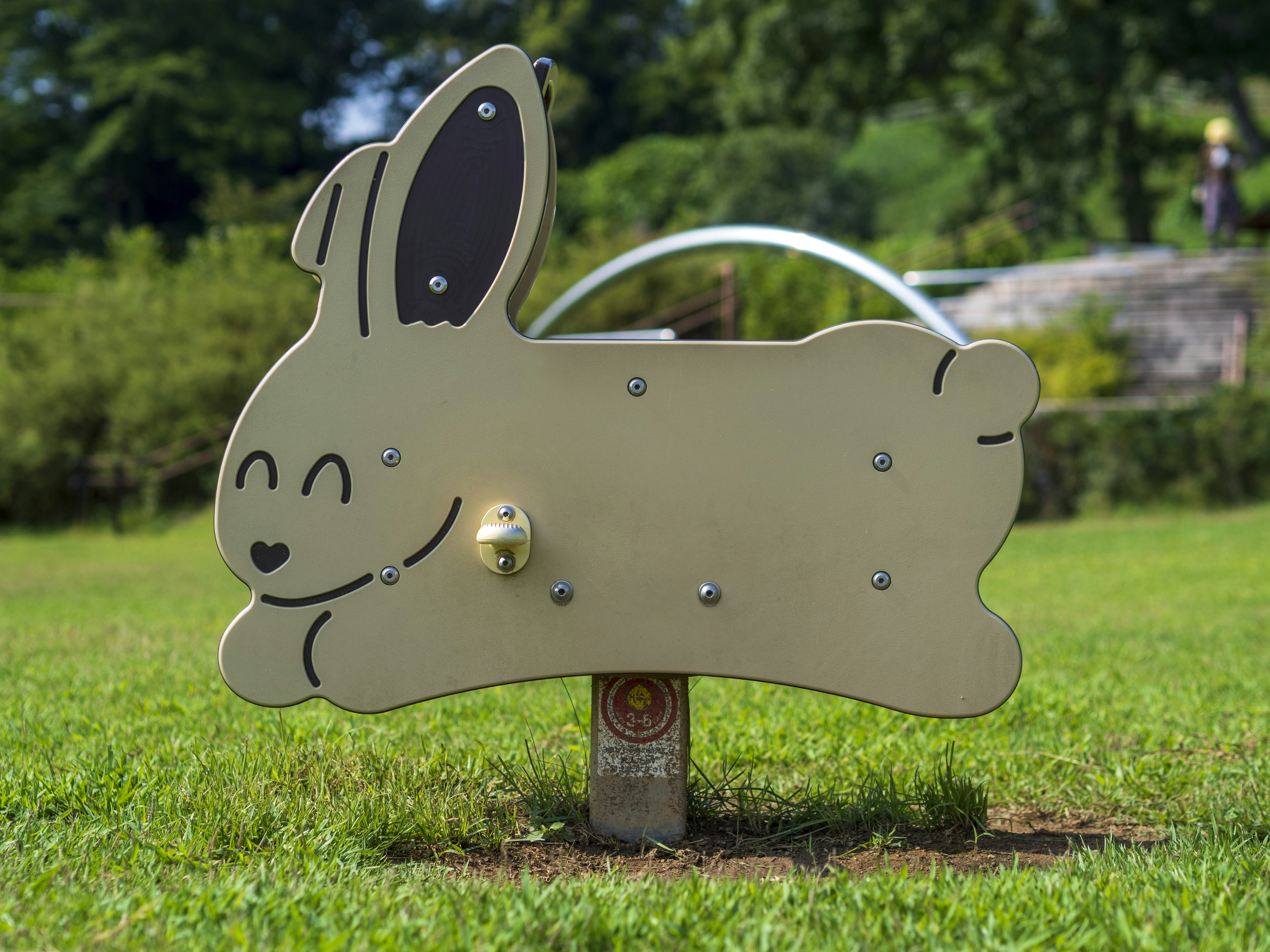 Hasenskulptur im Park mit lächelndem Design und metallischer Struktur