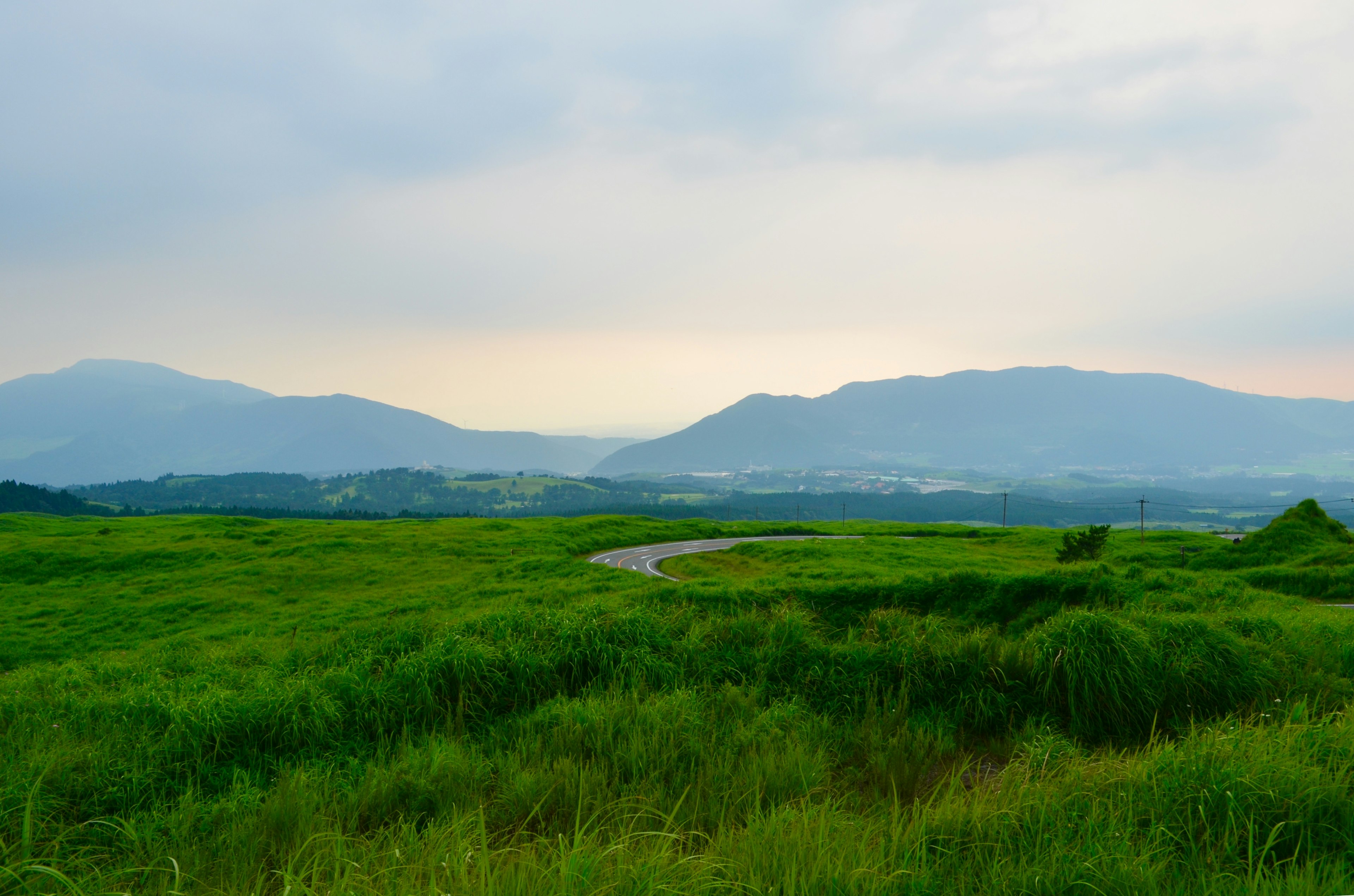 Lush green fields with rolling hills and distant mountains