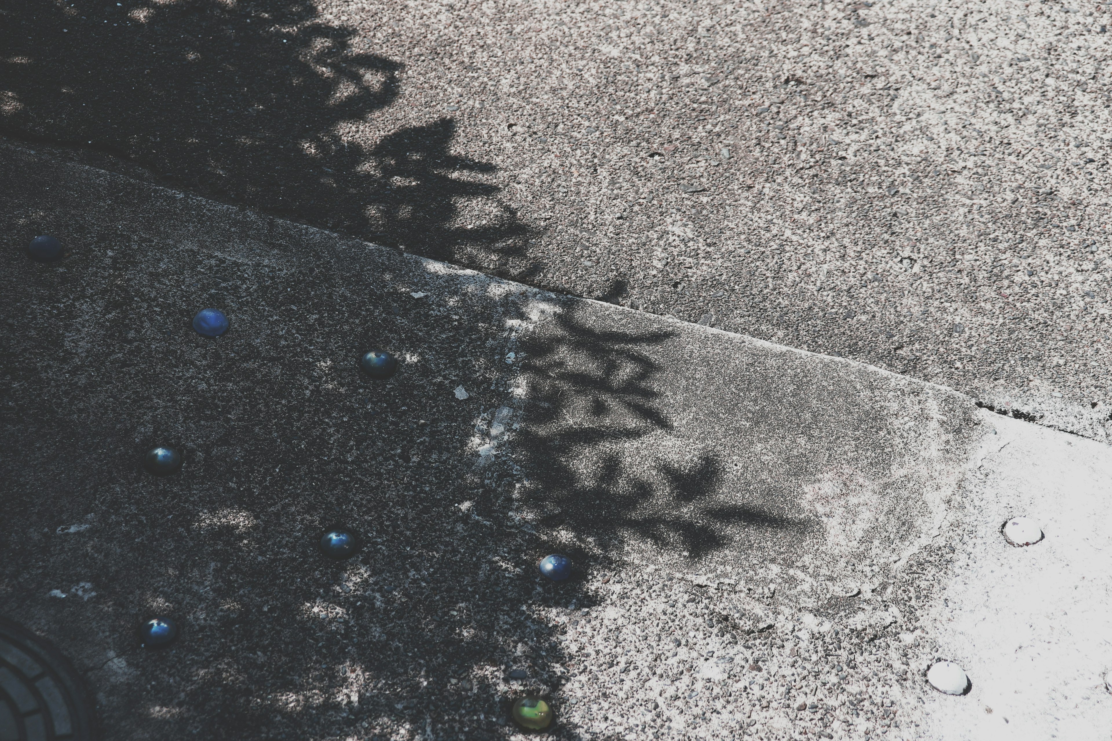 Concrete surface with shadows and colorful marbles