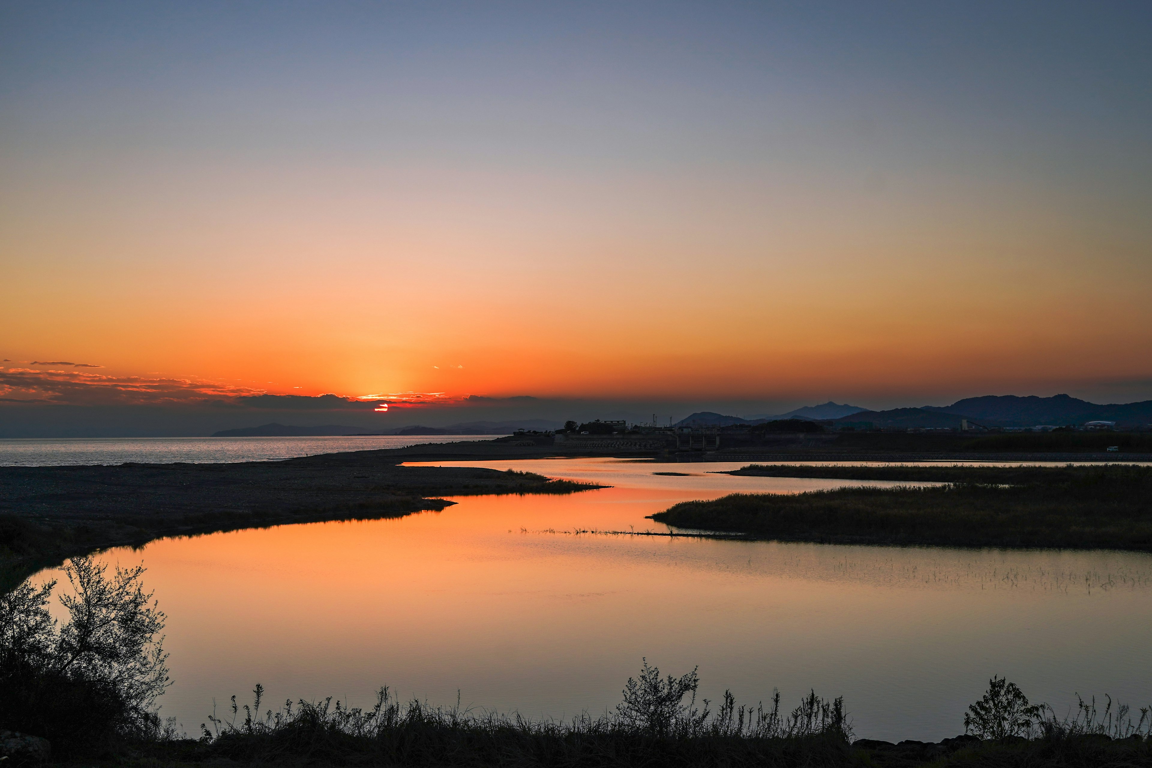 夕焼けの海と川の景色