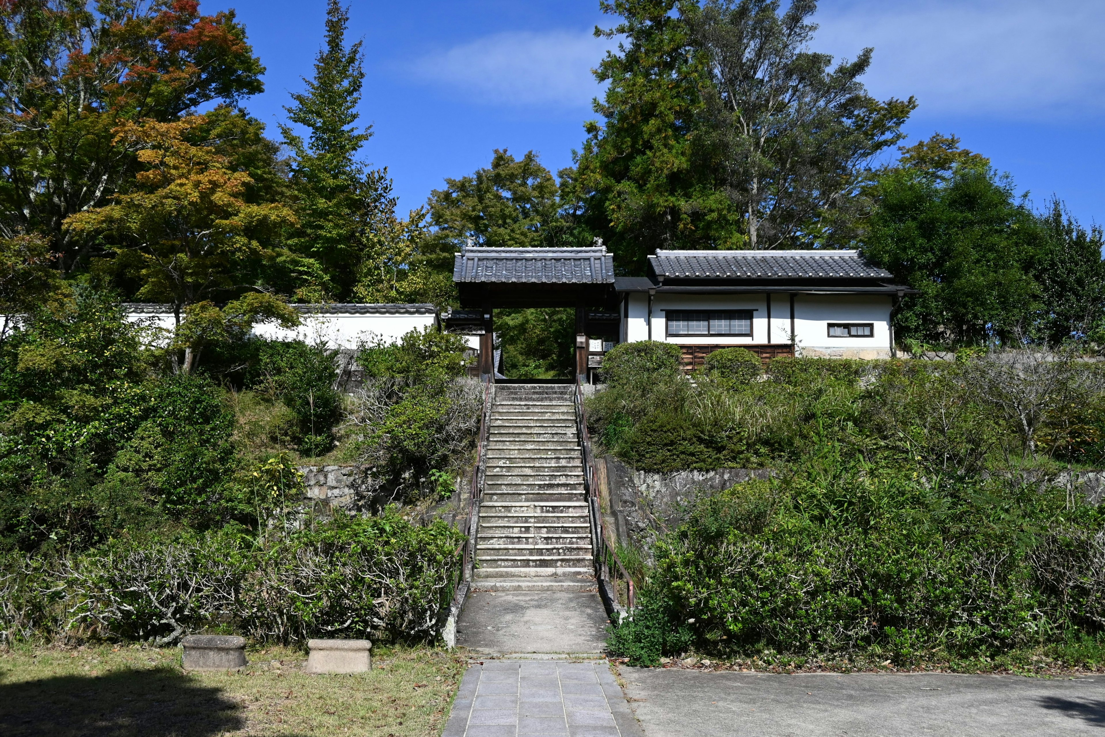 Stairs leading to a traditional Japanese house surrounded by greenery