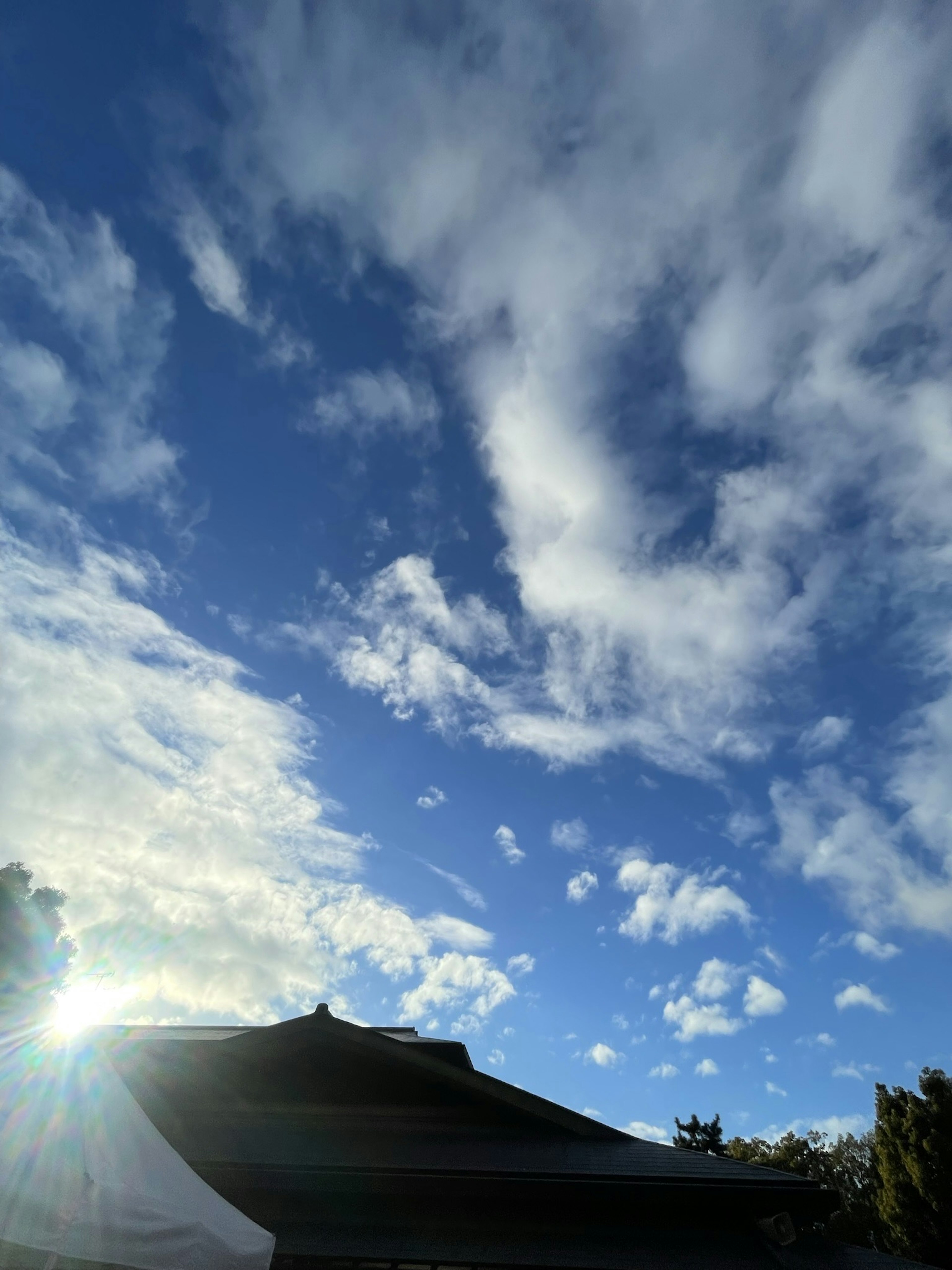 Clear blue sky with white clouds and a building roof