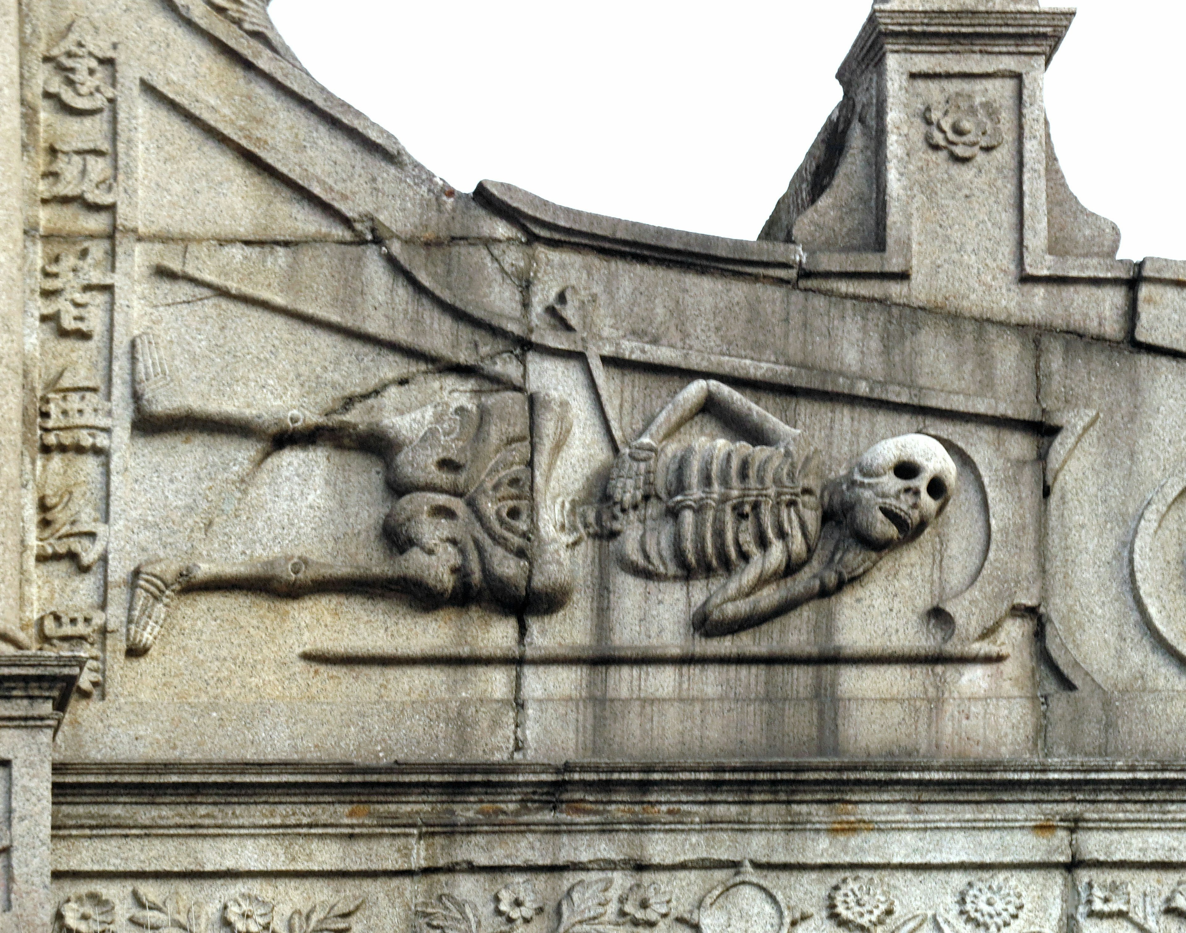 Sculpted skeleton and face on a stone wall