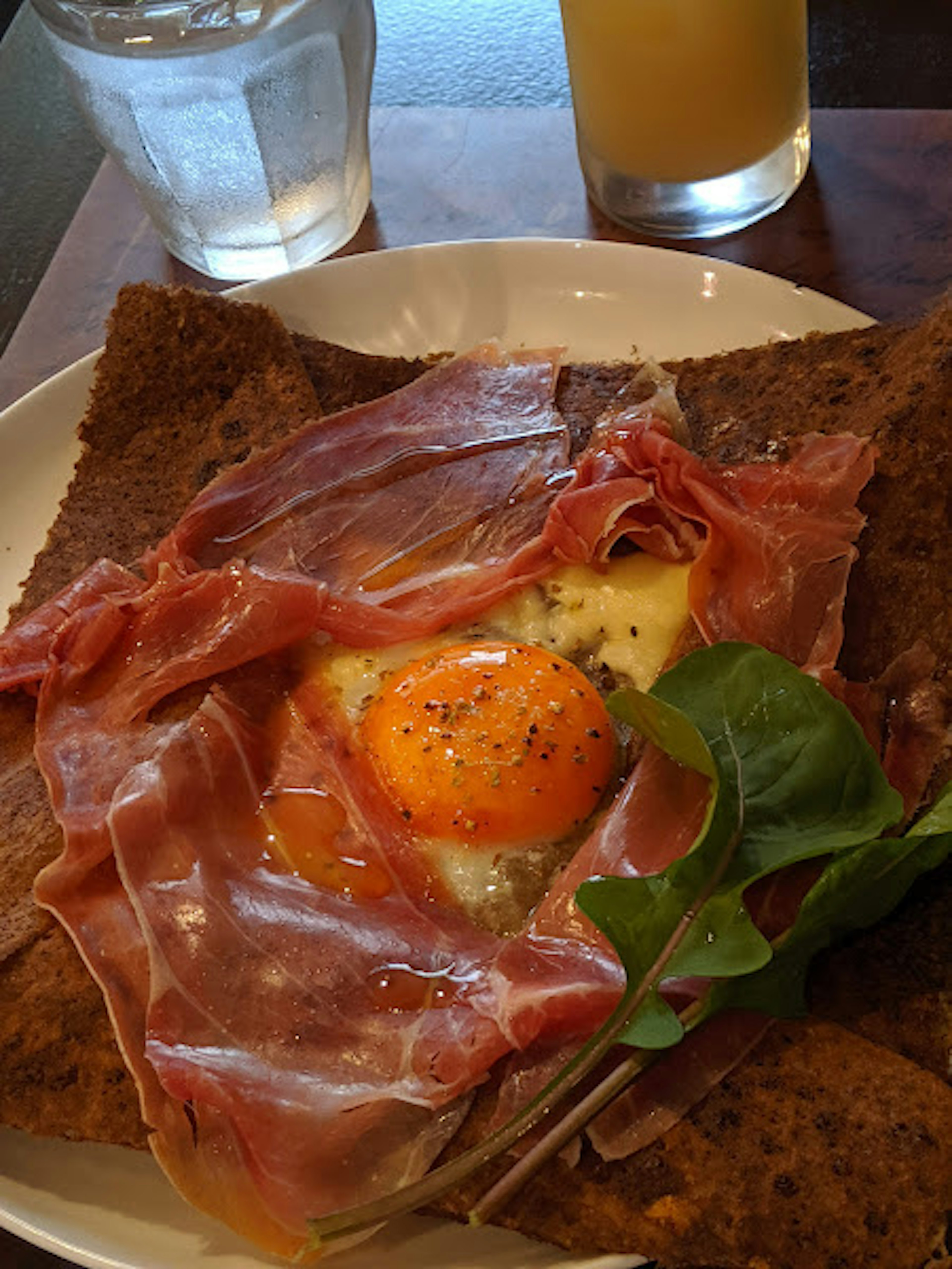 A plate of galette topped with ham and a sunny-side up egg