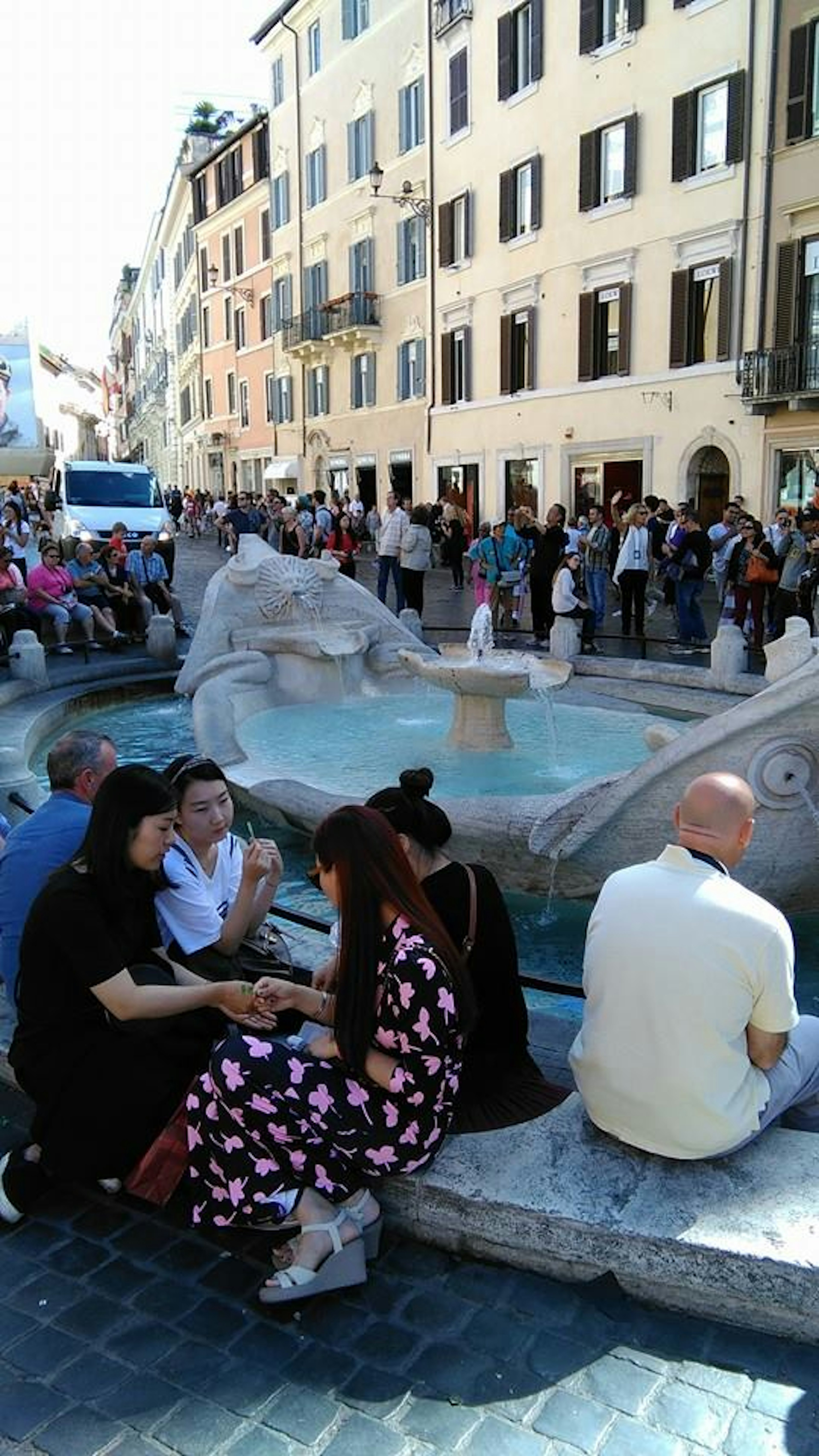 A beautiful fountain in a Roman square surrounded by people