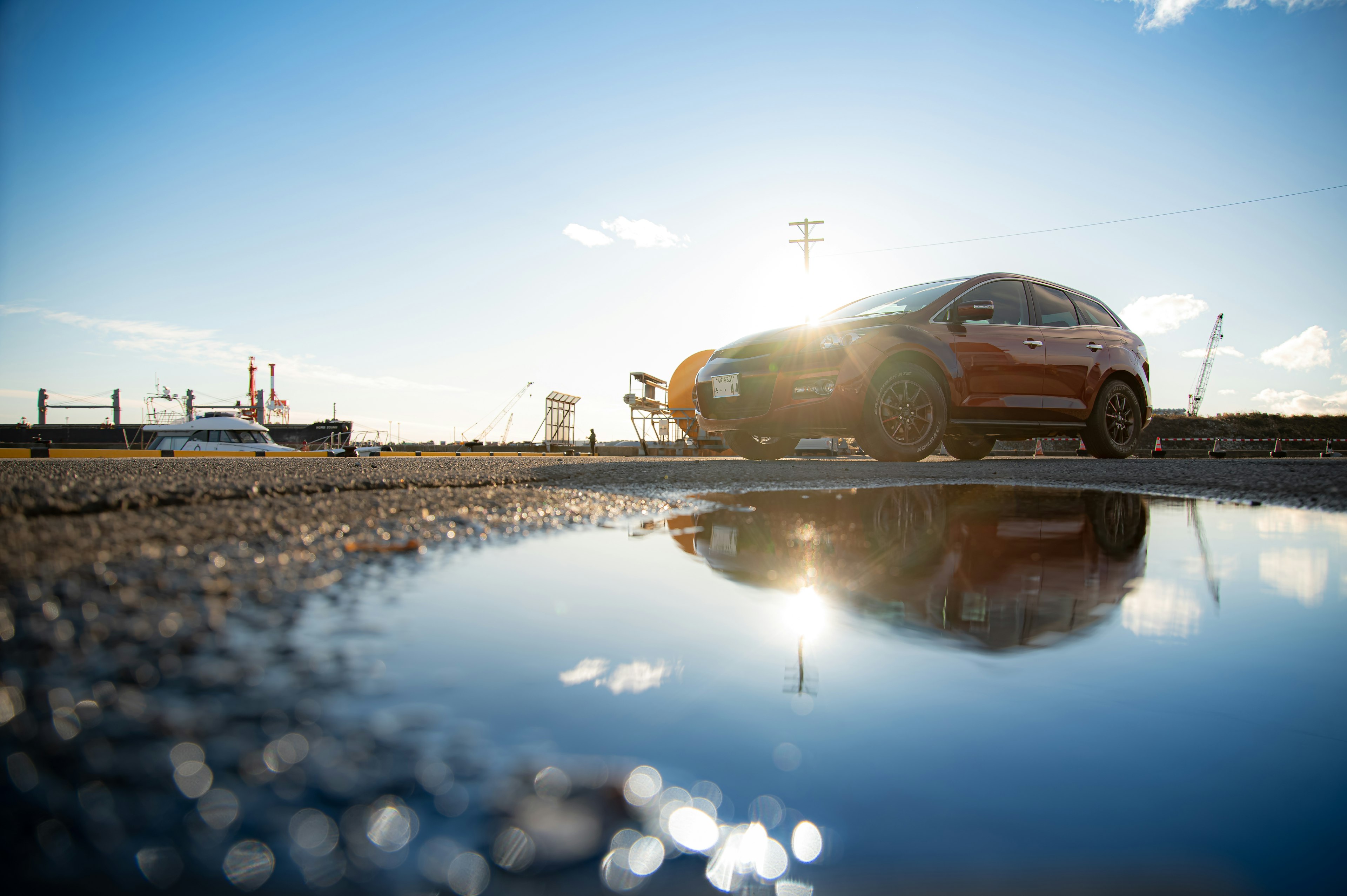 Red car reflected in a puddle with a blue sky