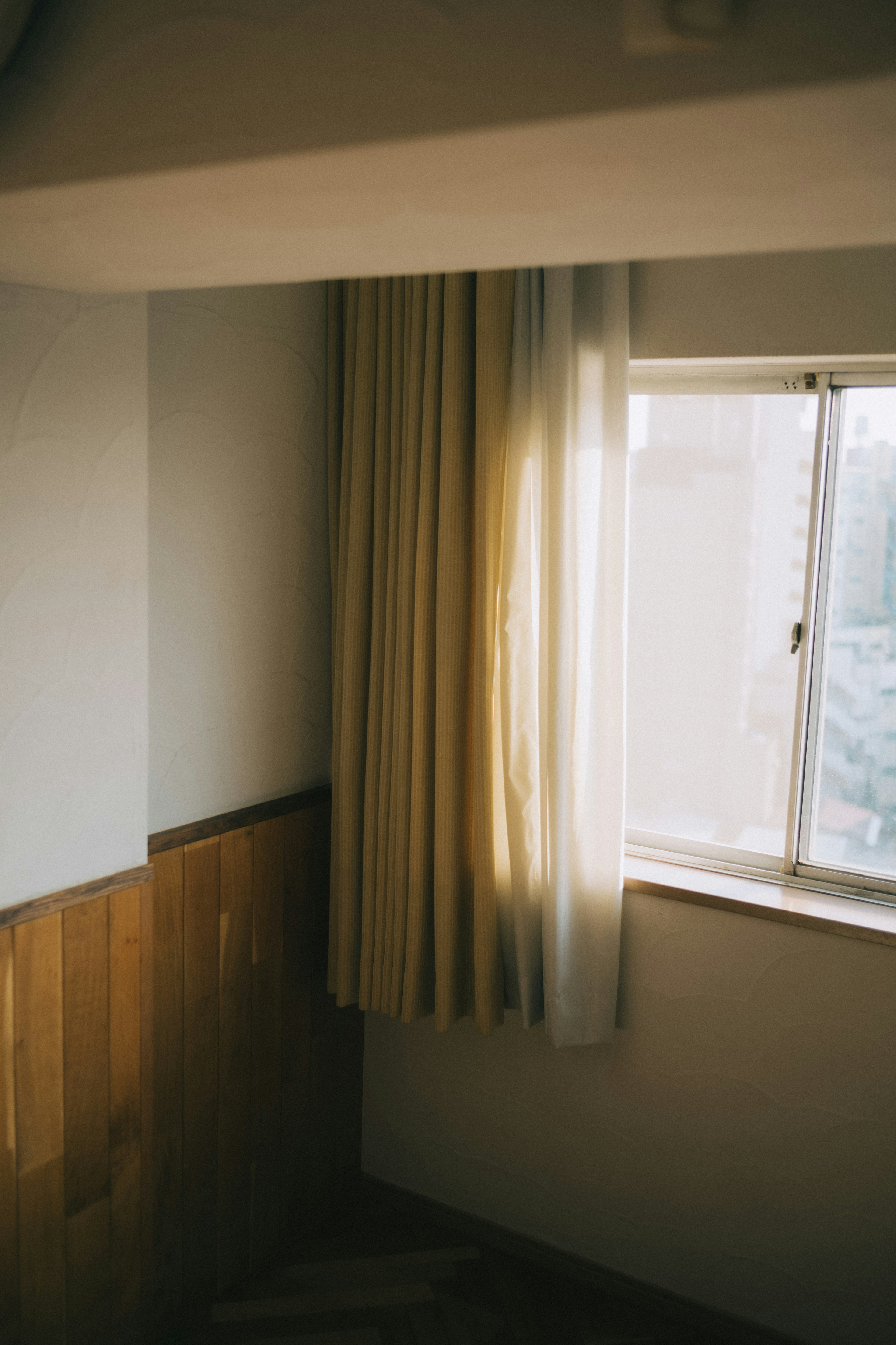 Corner of a room with bright curtains and wooden paneling