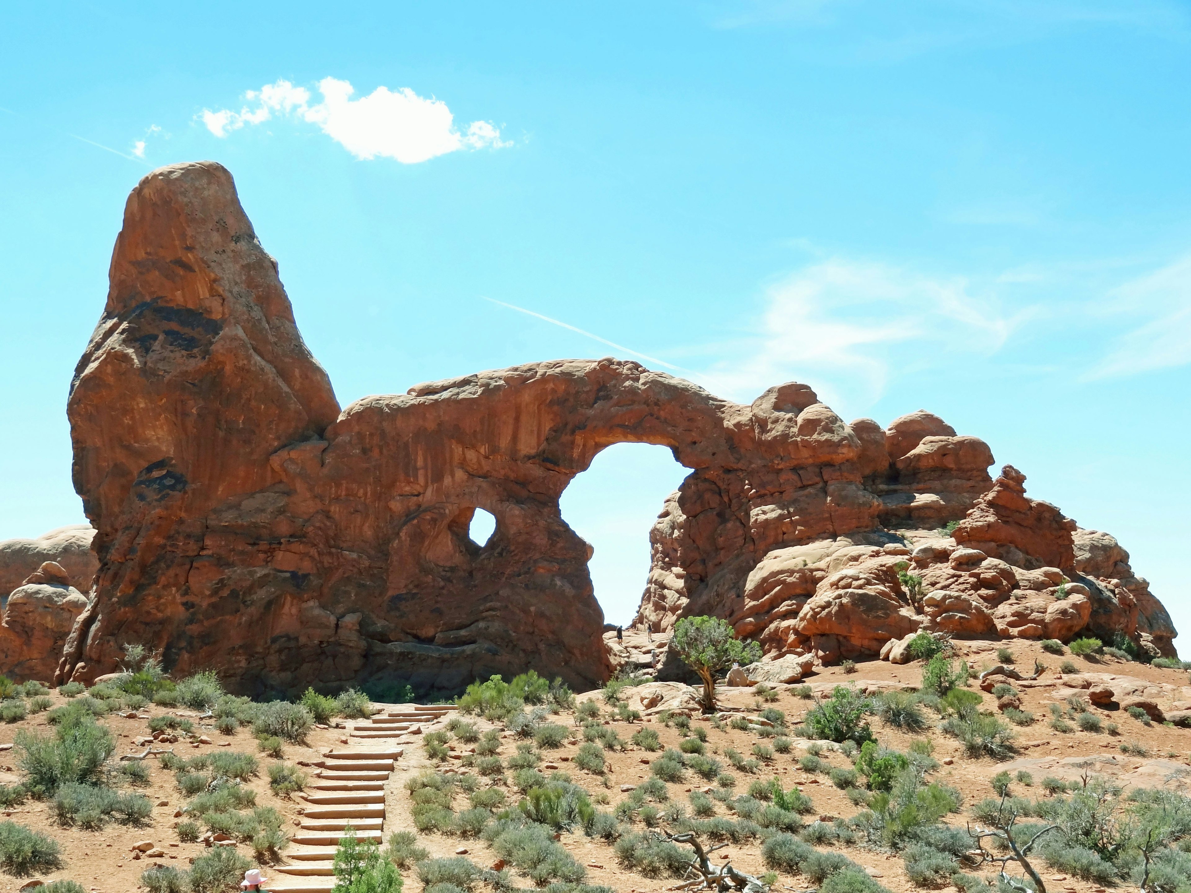 Paisaje natural con un arco de roca roja y arbustos circundantes