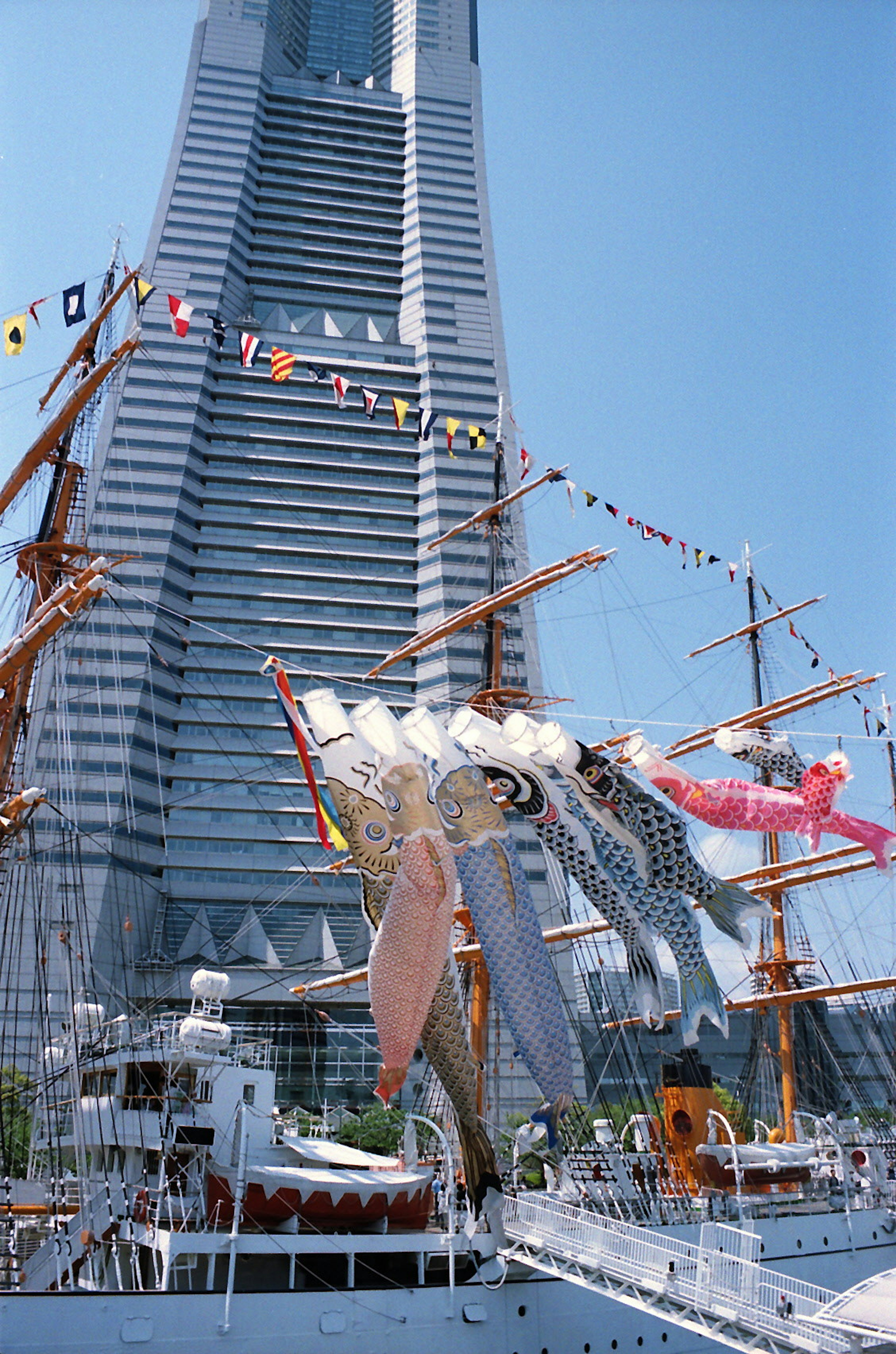 Hafenszene mit einem Hochhaus und traditionellen Segelschiffen