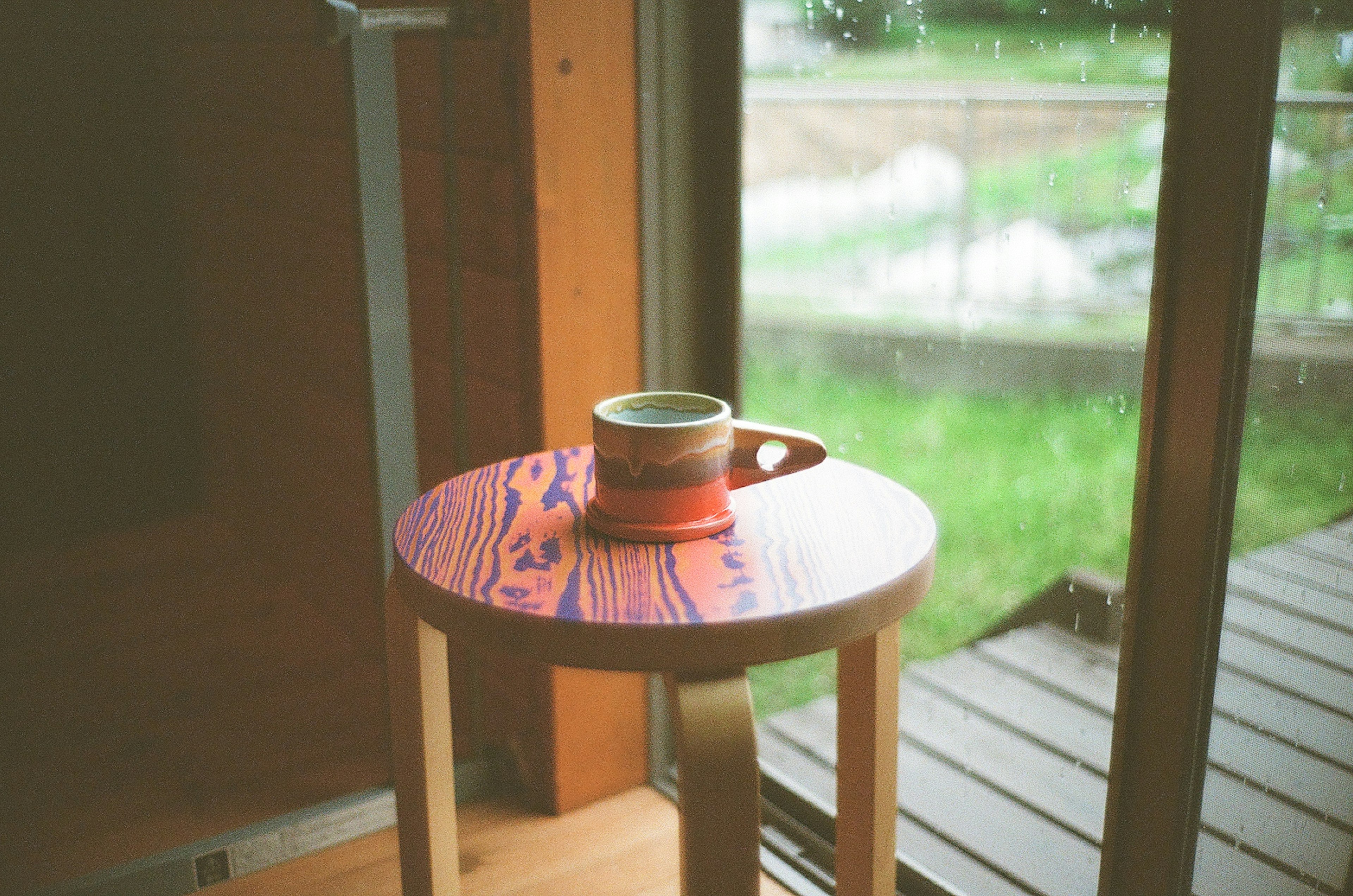 Tasse colorée sur une table à motifs près d'une fenêtre avec de la verdure à l'extérieur