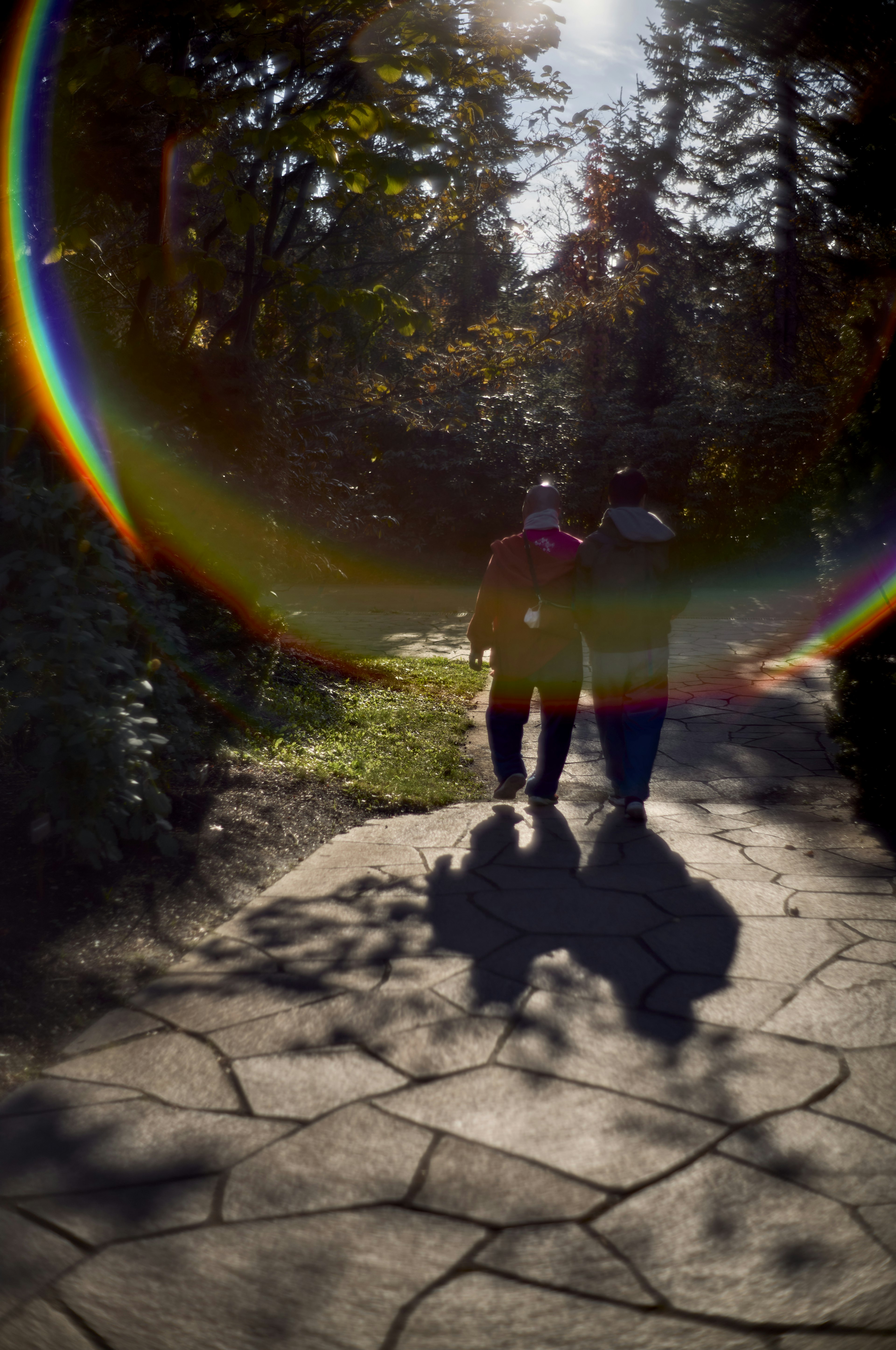 Zwei Personen, die im Sonnenlicht gehen, mit Schatten und einem Regenbogenhalo