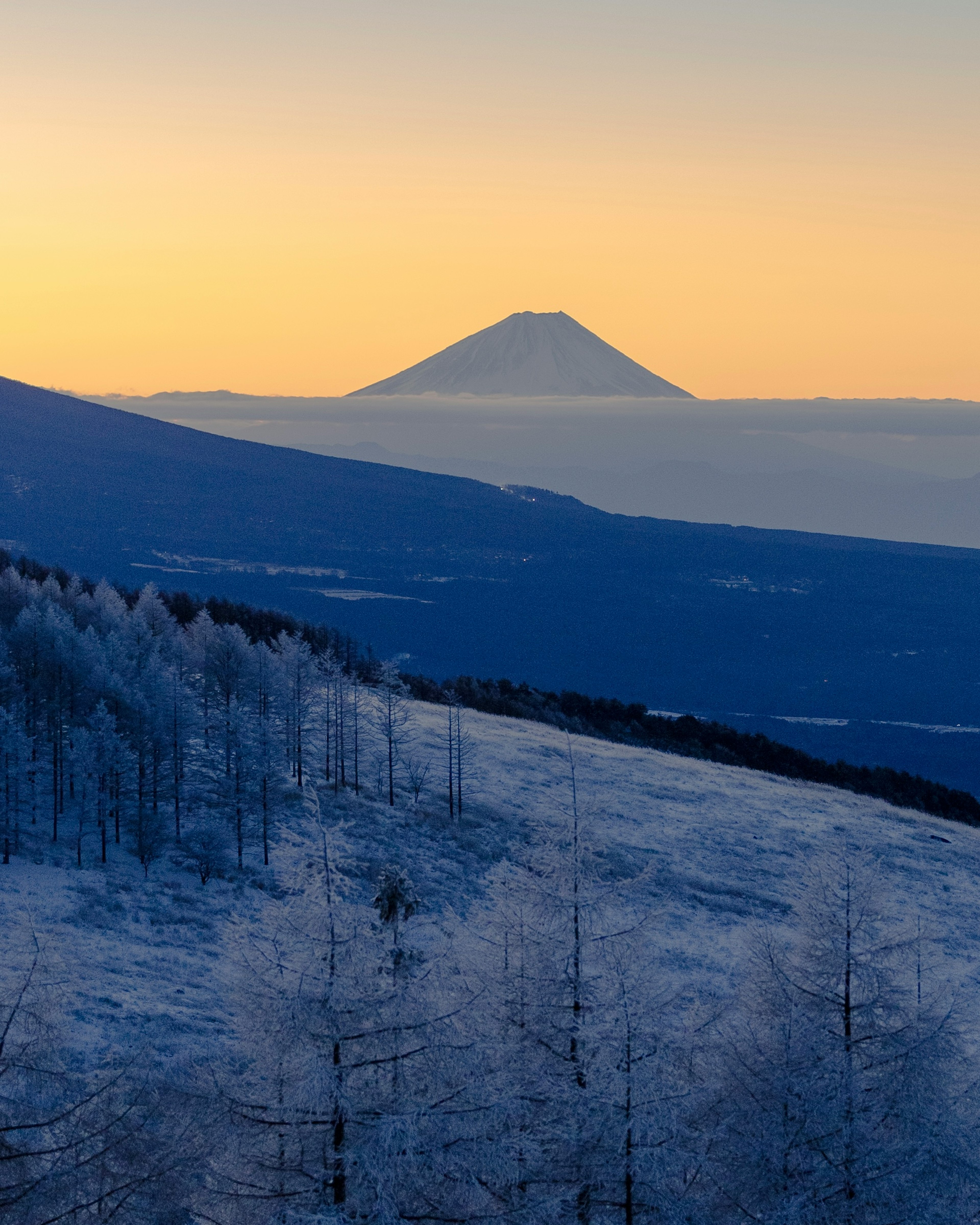 Schneebedeckte Berglandschaft mit der Silhouette des Fuji im Hintergrund