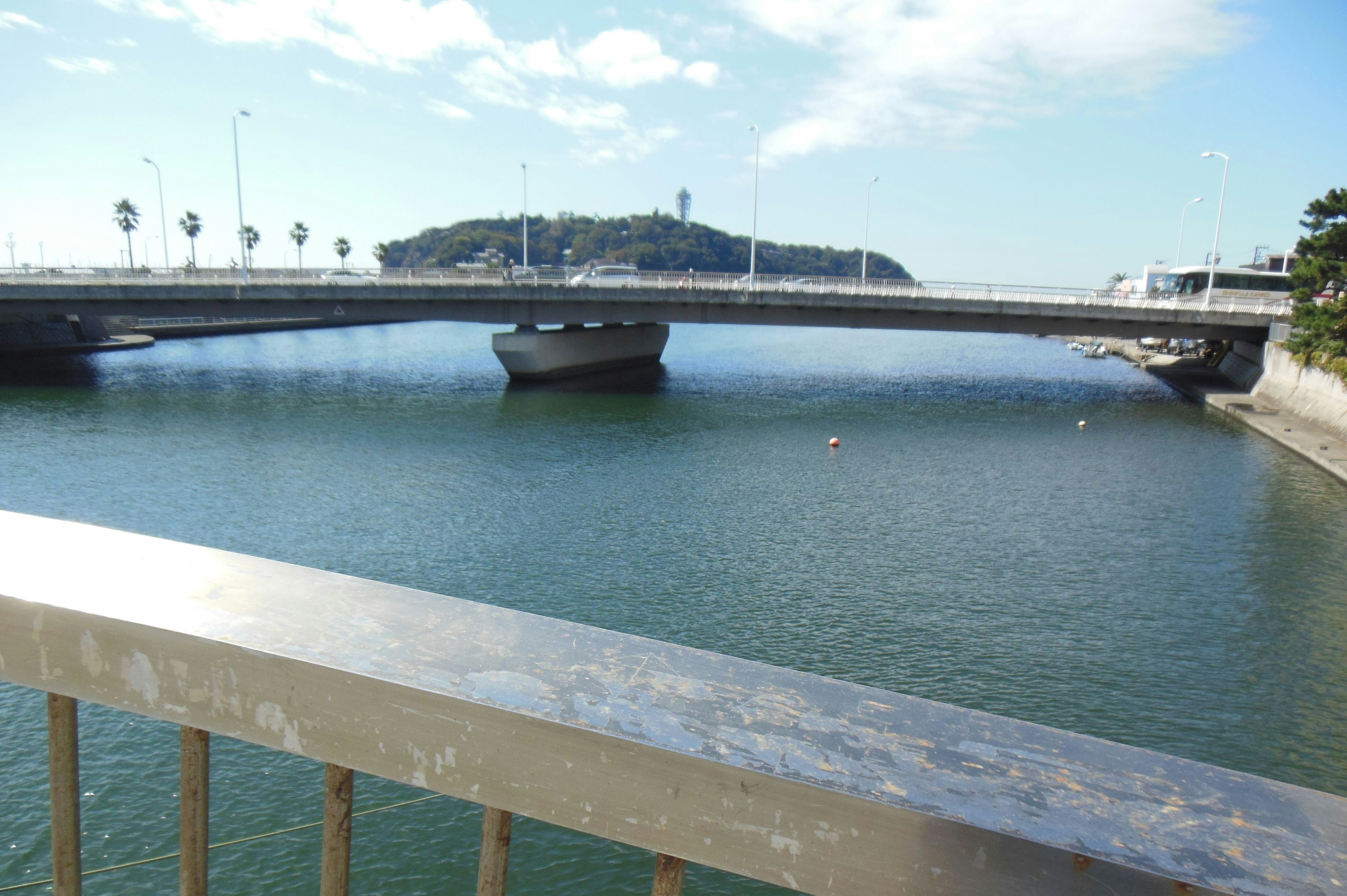 Bridge over calm waters with distant hills and palm trees