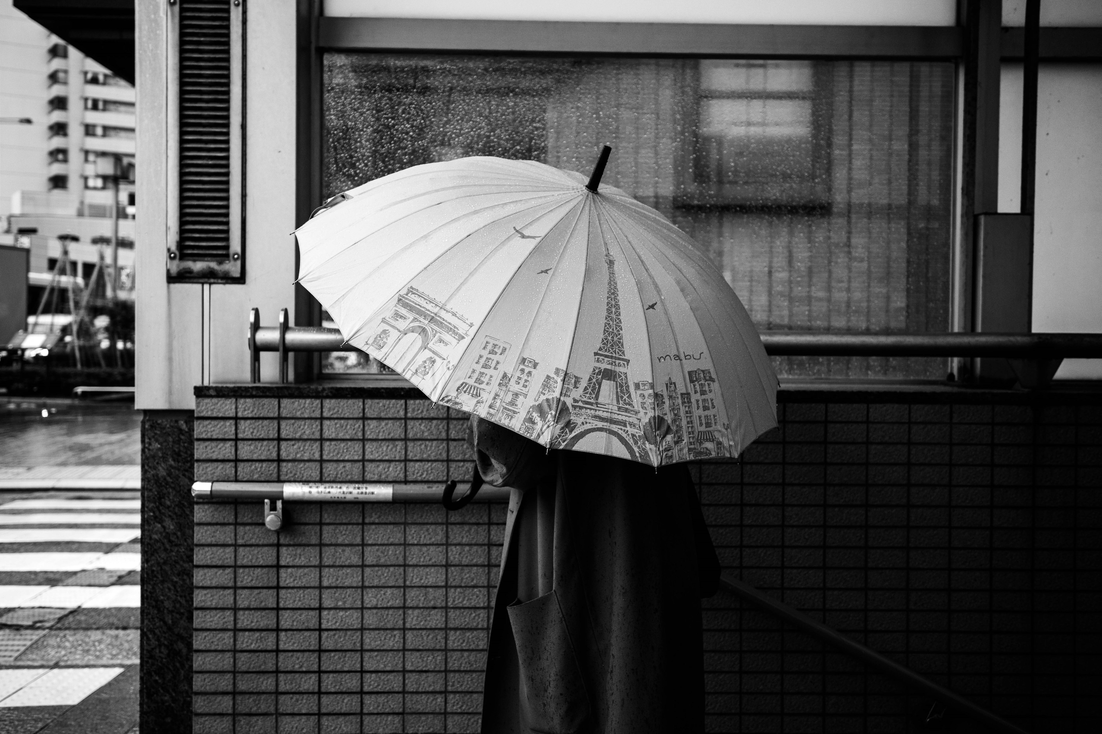 A person walking in front of a building holding a black and white umbrella