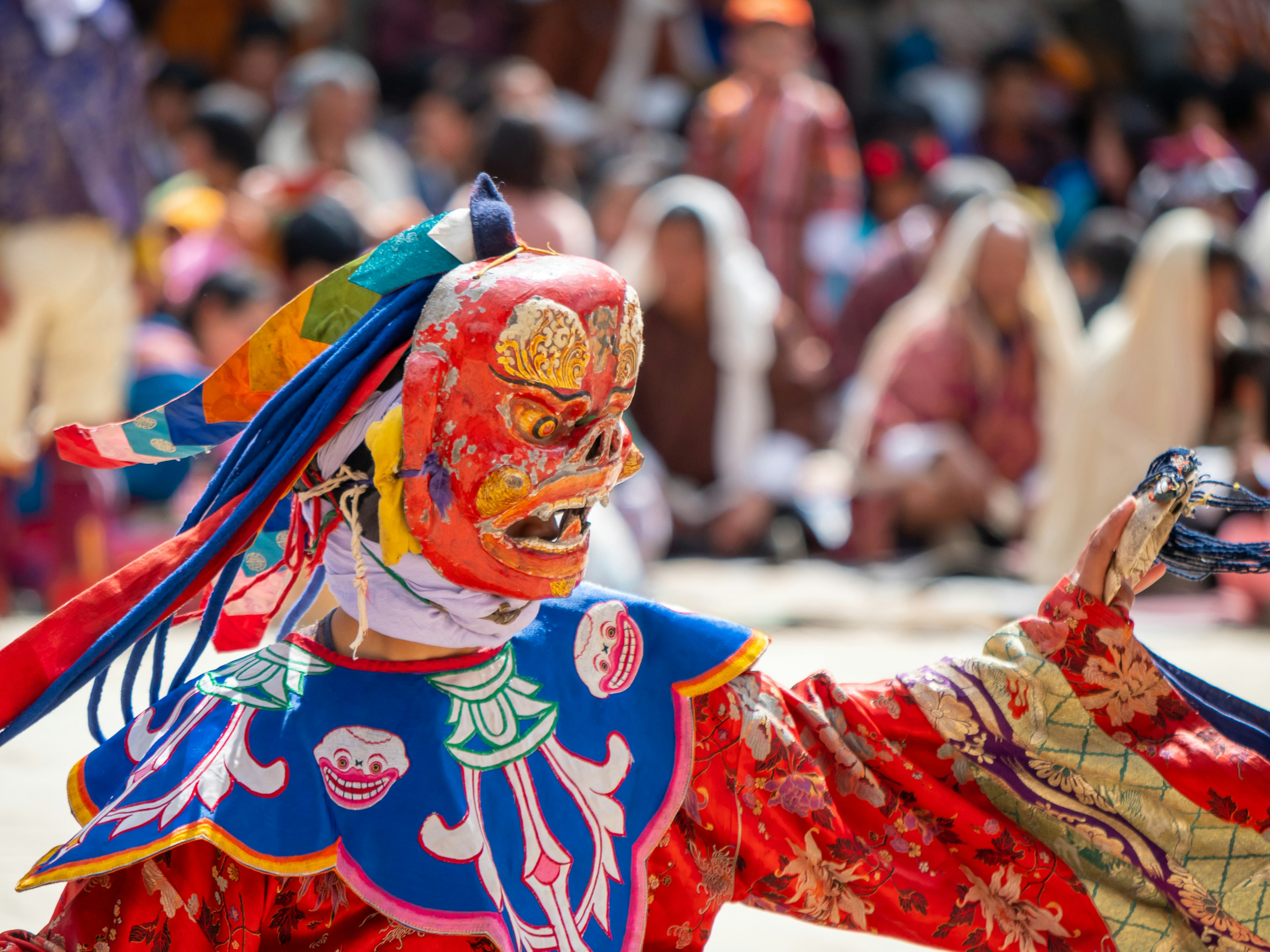 Scène de festival traditionnel avec un danseur portant un costume coloré et un masque