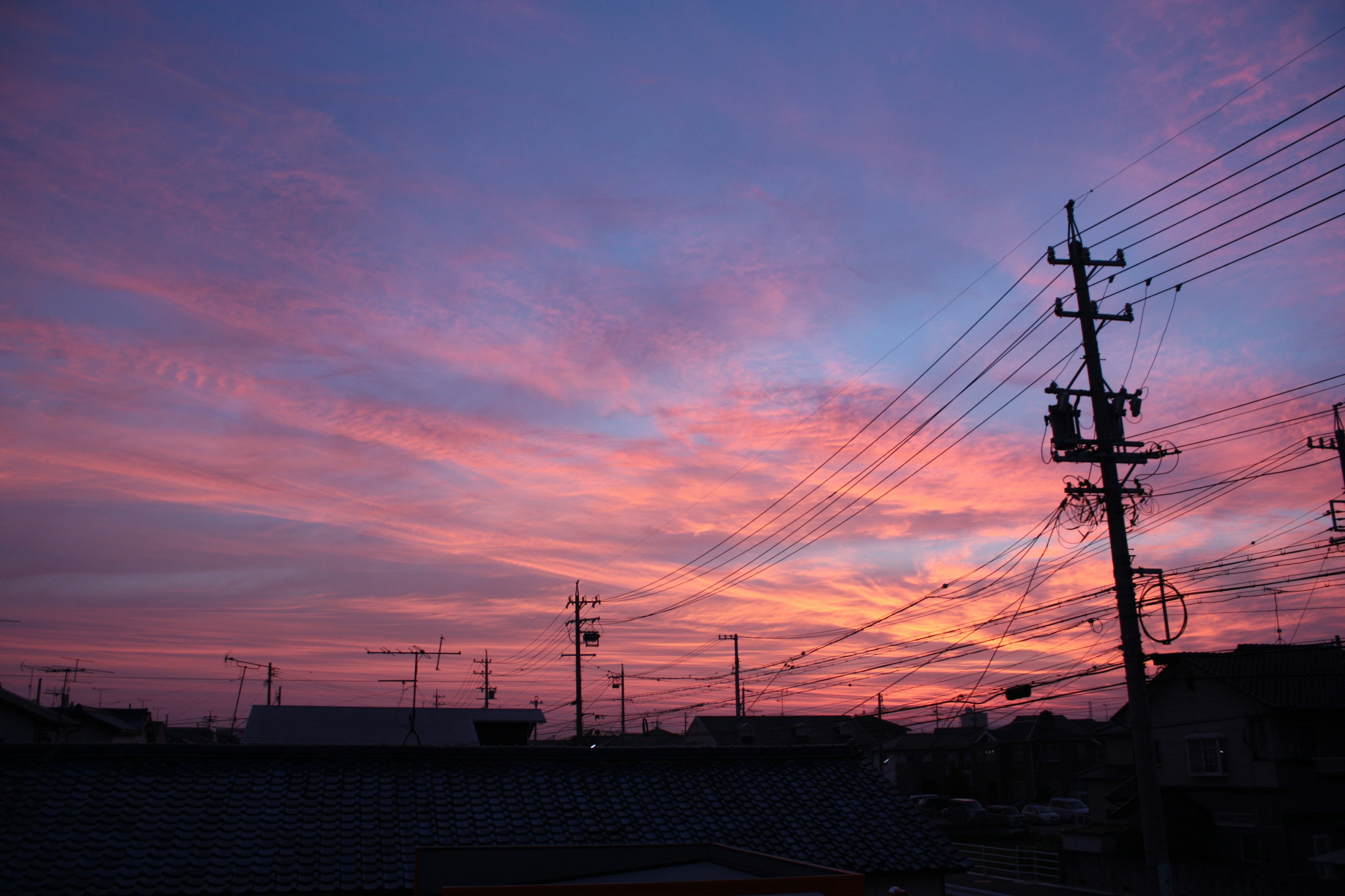 Nubes rosas y moradas vibrantes en un cielo de atardecer con líneas eléctricas en silueta